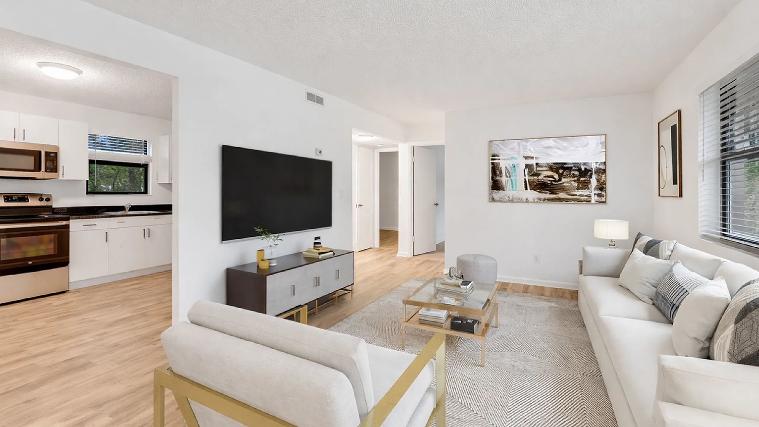 Bright and modern living space featuring an elegant living room with plush seating, stylish decor, and an adjacent open-plan kitchen with sleek appliances.