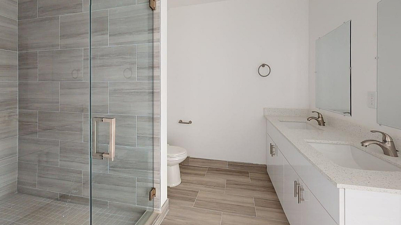 Contemporary bathroom featuring a sleek glass shower, double vanity with modern fixtures, and elegant tile flooring.