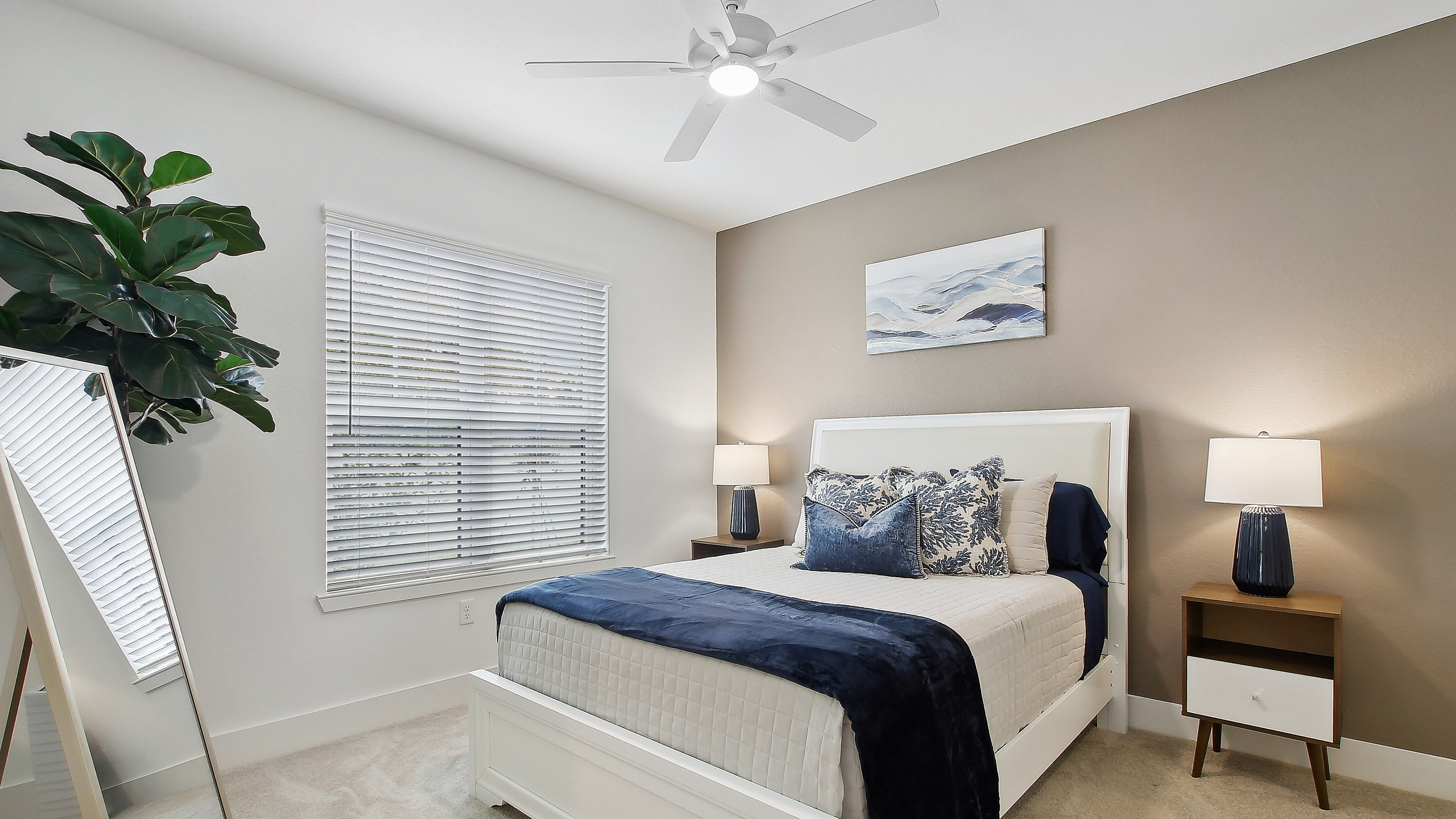 Elegant bedroom with modern decor featuring a comfortable white bed, stylish throw pillows, and ambient lighting. Large window with blinds and a lush indoor plant add a refreshing touch.