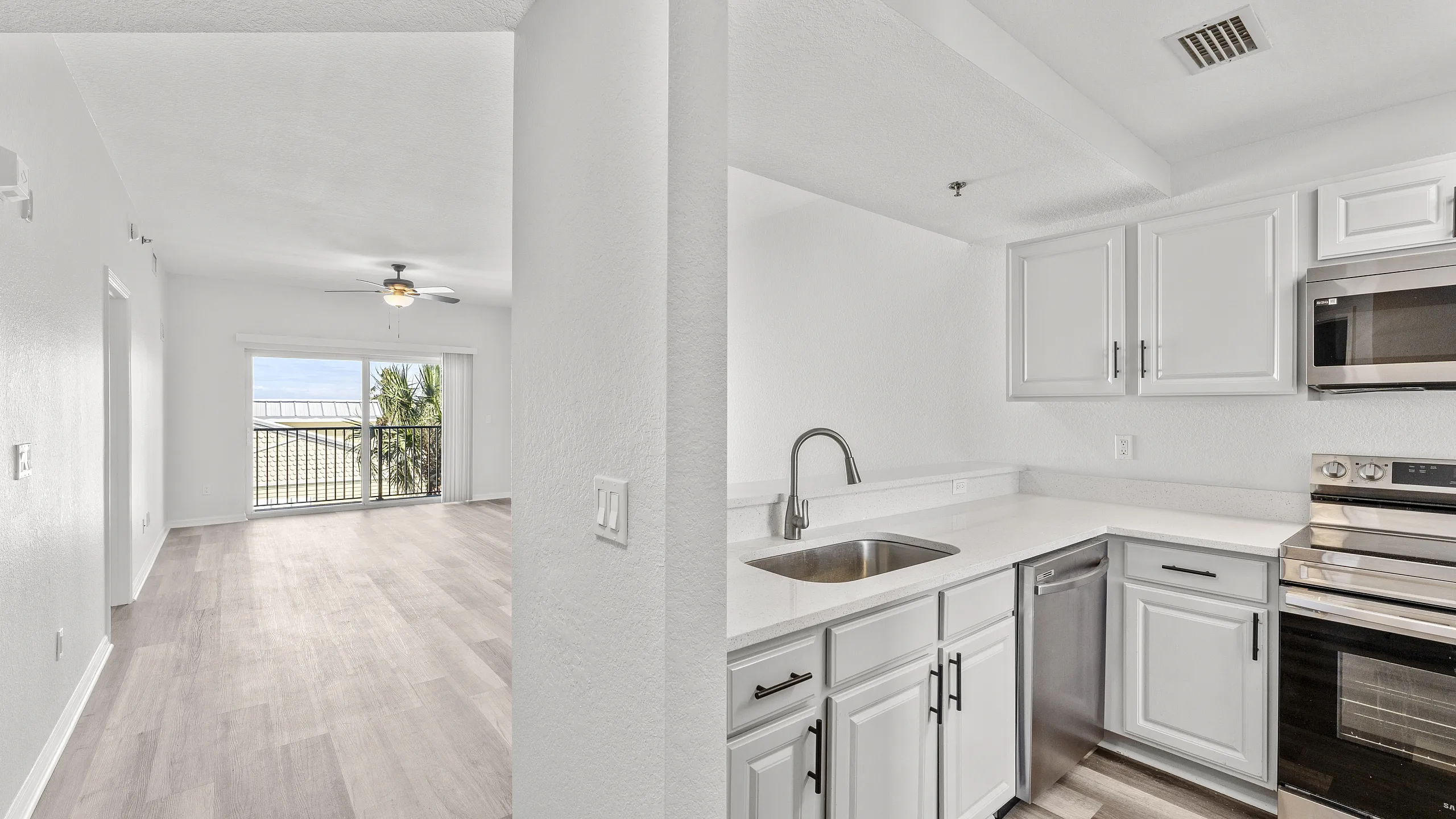 Bright, contemporary apartment with a modern stainless steel kitchen, elegant wood flooring, and a scenic balcony view.