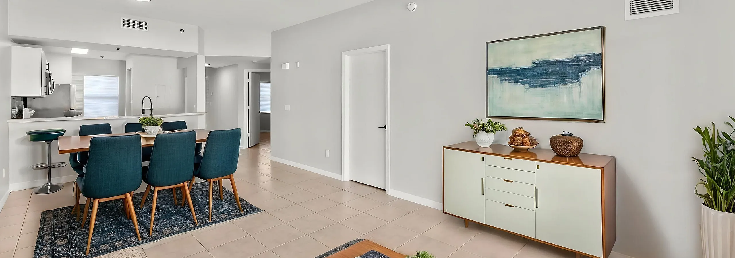 Modern open-concept living and dining area with stylish blue chairs, elegant ceiling fan, and chic decor, perfect for entertaining in comfort.