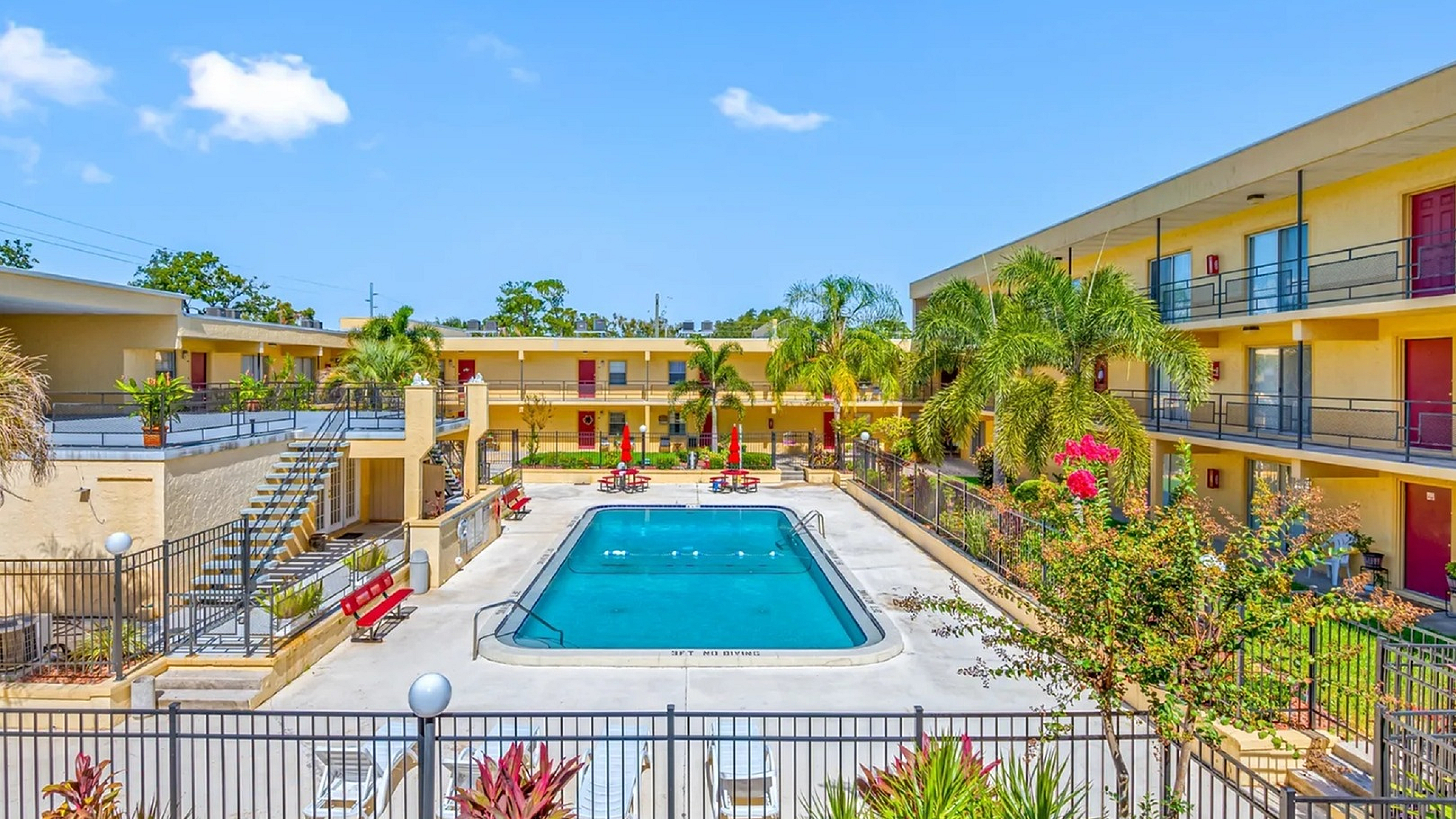 Vibrant apartment complex with a sparkling central swimming pool, surrounded by lush greenery and modern architecture.