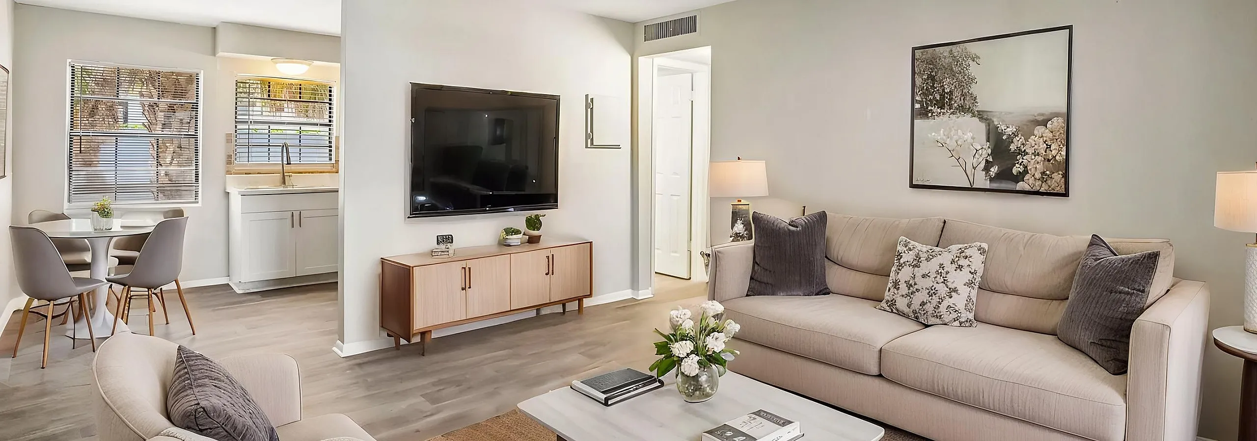Bright and cozy living room with a modern beige sofa, stylish armchairs, and a sleek coffee table, seamlessly flowing into a chic dining area with ample natural light.