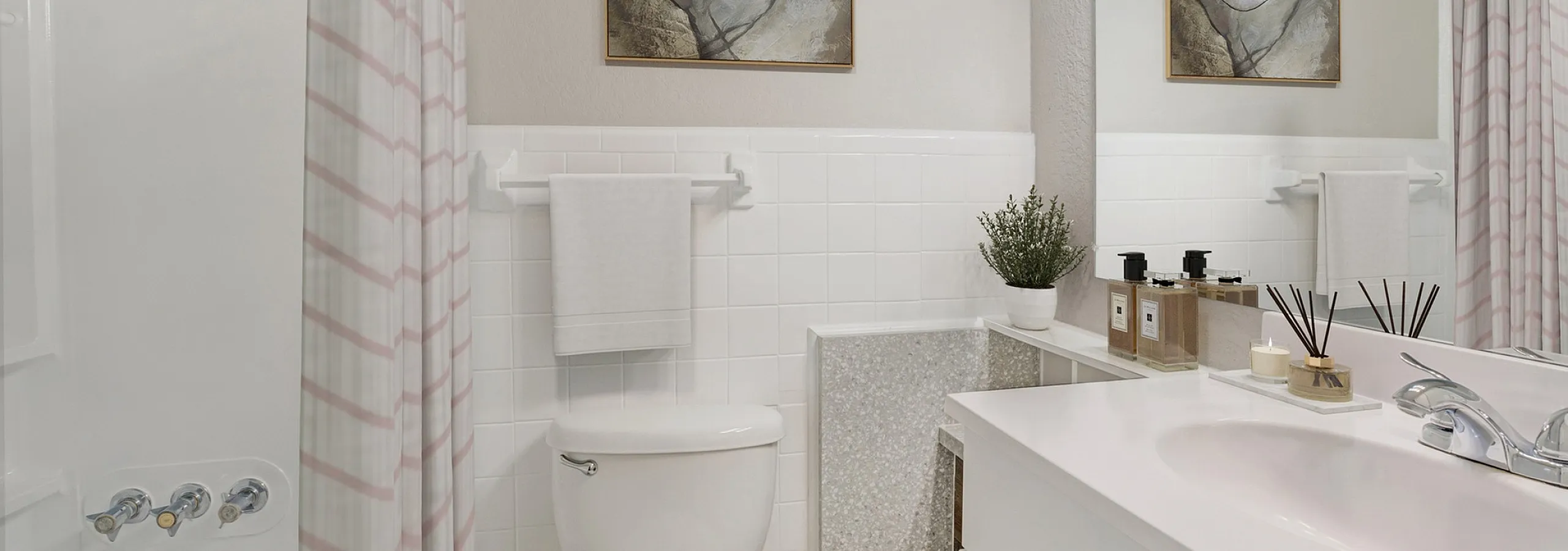Elegant and modern bathroom featuring sleek white tiles, stylish artwork, and contemporary fixtures, offering a serene and inviting atmosphere.