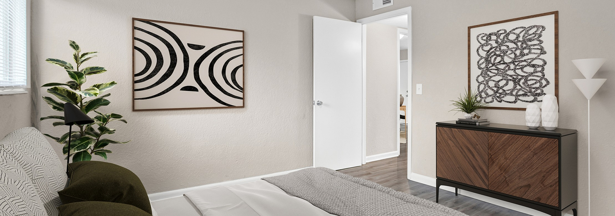 Cozy bedroom with modern d&eacute;cor, featuring stylish abstract art, a sleek chest of drawers, and a soft, inviting bed with dark pillows.