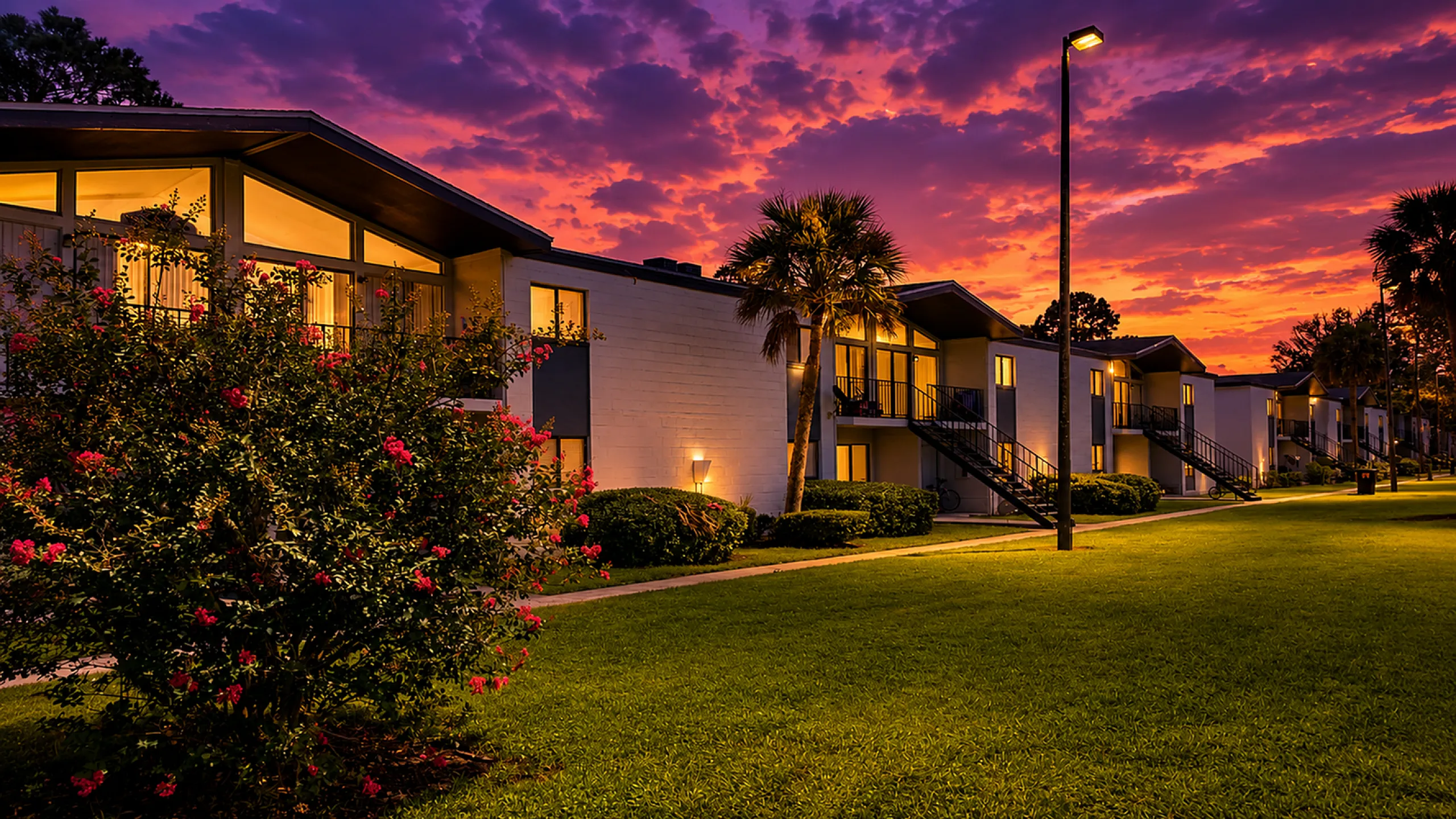 Charming apartment complex at sunset, with vibrant landscaping and a serene atmosphere.