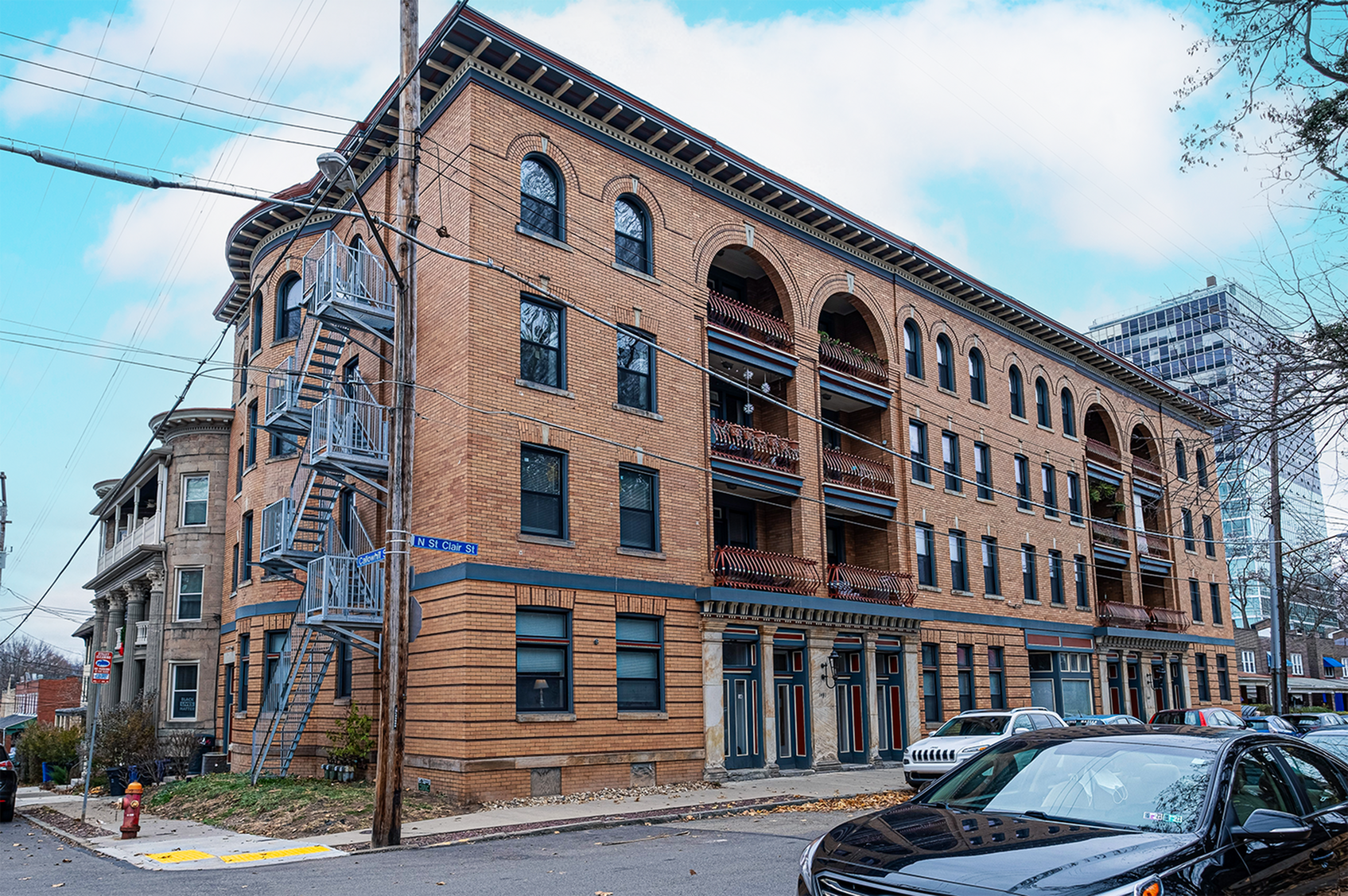Elegant brick apartment building with arches and balconies on the corner of a quiet street.