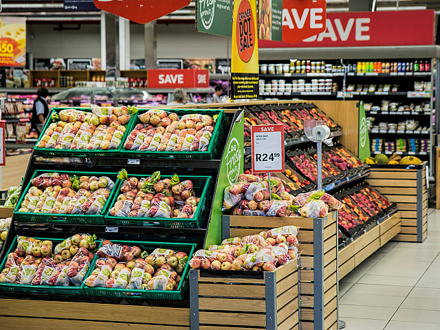 Vibrant grocery store aisle showcasing fresh apples on display, with eye-catching discounts and sales signs, inviting shoppers to save on delicious produce.