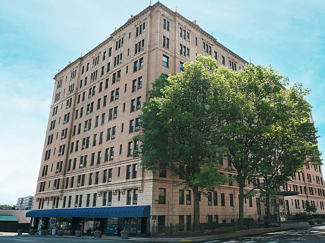 Charming historic apartment building with elegant architecture, nestled in a vibrant cityscape, surrounded by lush green trees.
