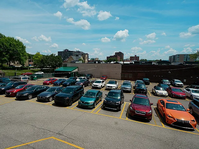 Spacious urban parking lot with diverse vehicles under a clear blue sky, showcasing convenient city access.