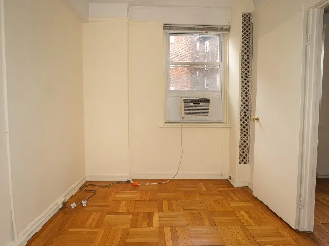 LeBaron unit bedroom, with cream walls and parquet hardwood flooring.