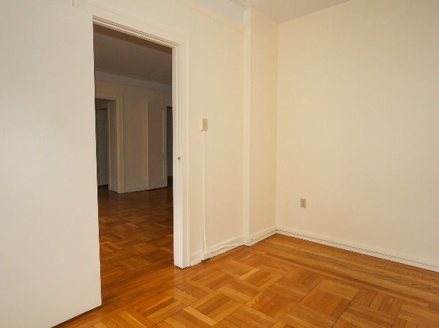 LeBaron unit bedroom, with cream walls and parquet hardwood flooring.