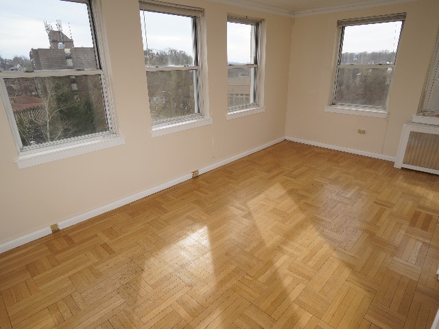 Artena unit showing living room with large windows, cream colored walls, and hardwood flooring.