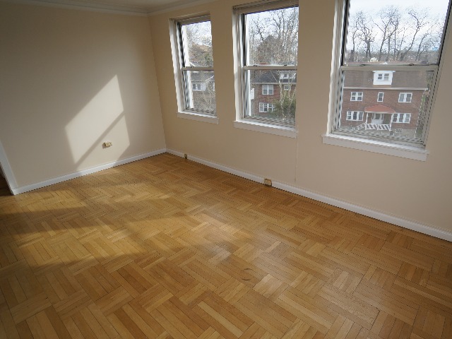 Artena unit showing living room with large windows, cream colored walls, and hardwood flooring.