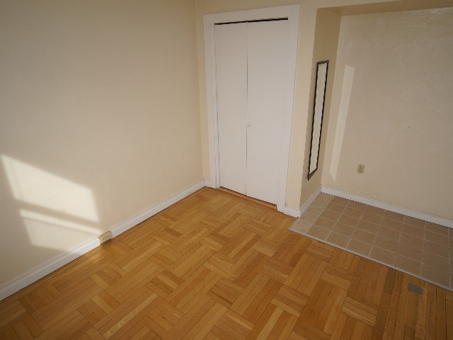 Artena unit showing bedroom with closet, cream colored walls, and hardwood and tan colored tile flooring.