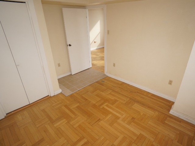 Artena unit showing bedroom with closet, cream colored walls, and hardwood and tan colored tile flooring.