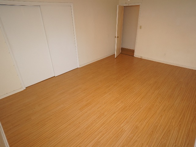 Talbot unit showing bedroom with cream colored walls, and hardwood vinyl flooring.