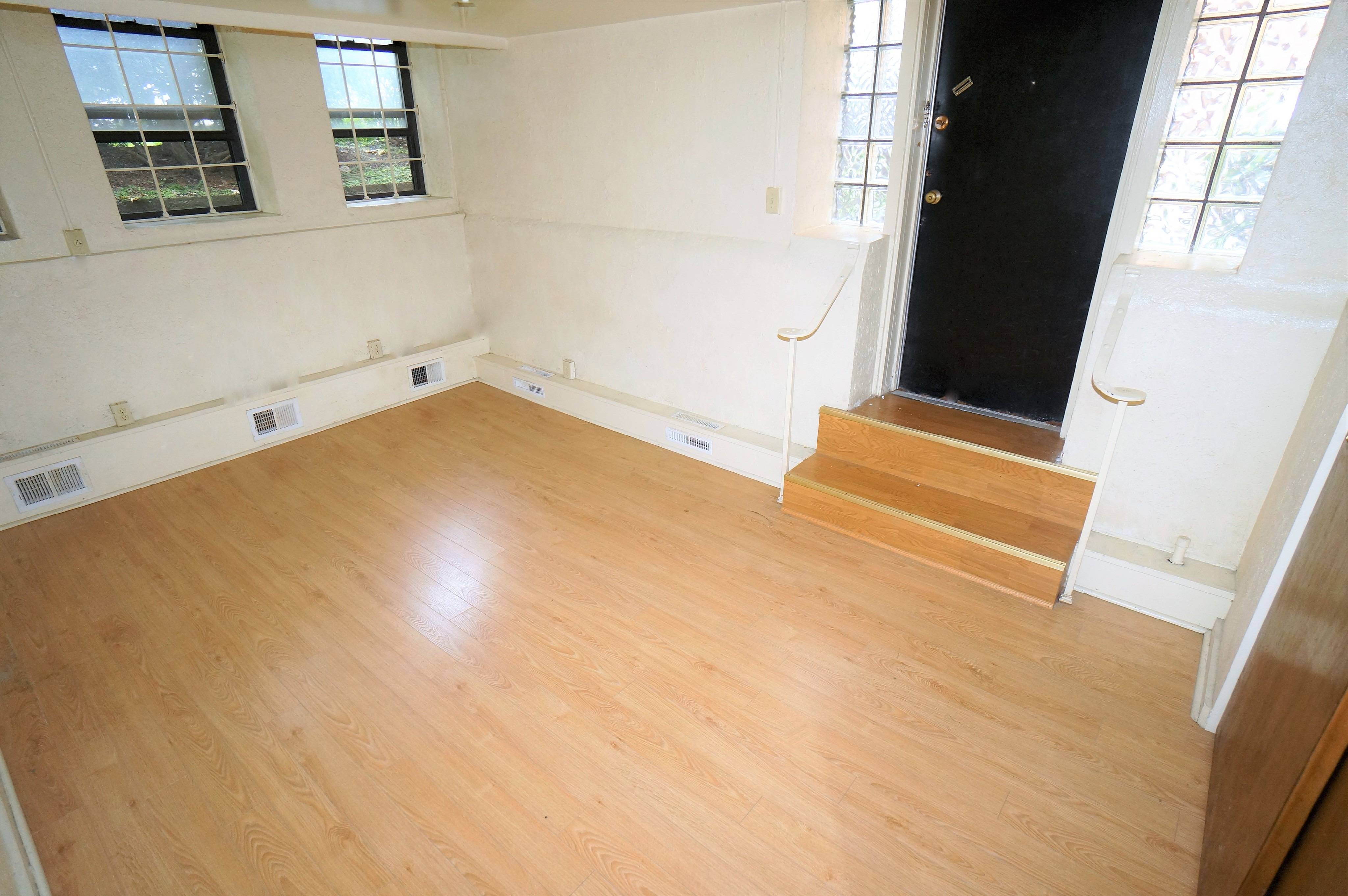 Living room angle shows windows, entry door and steps down to the room