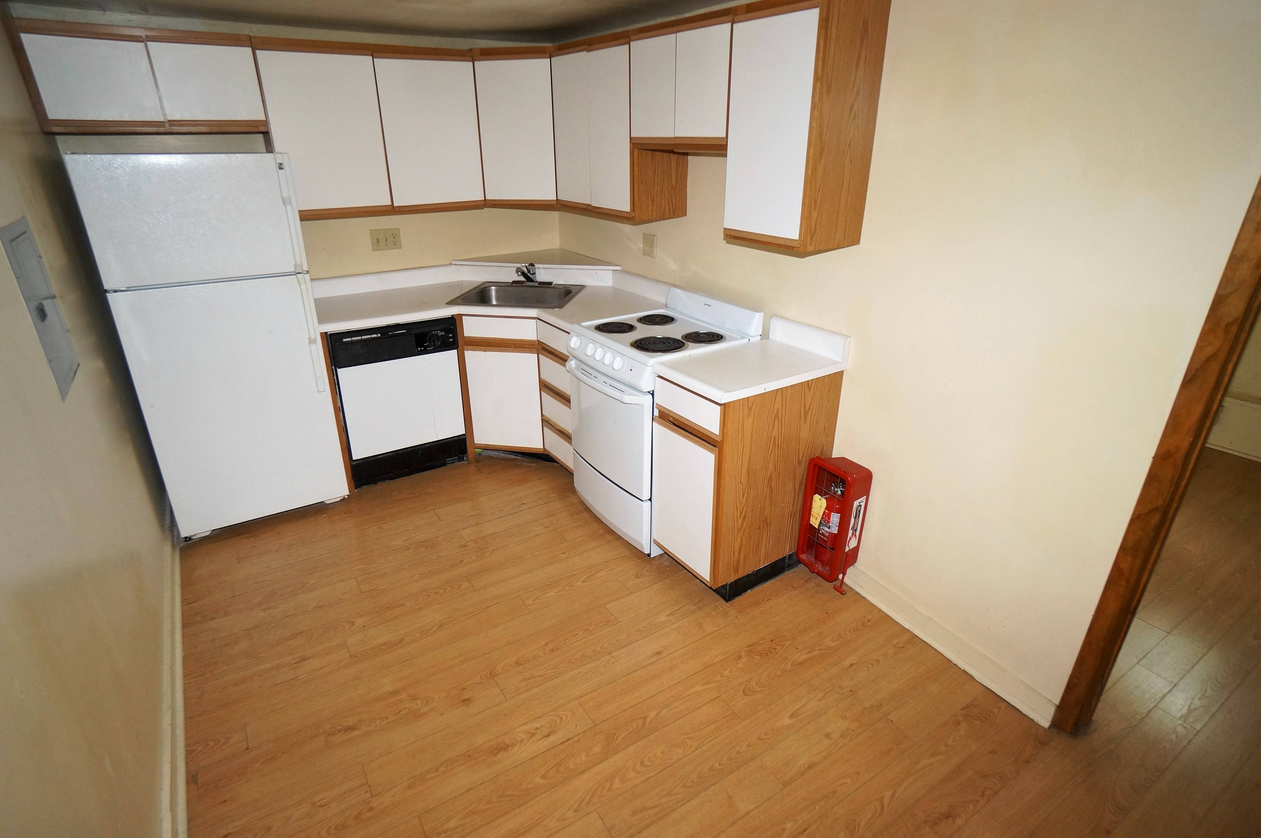 Kitchen shown has tile flooring, with white wood cabinets, Light counters, as well as a white fridge, and white gas oven/stove combination and a dishwasher