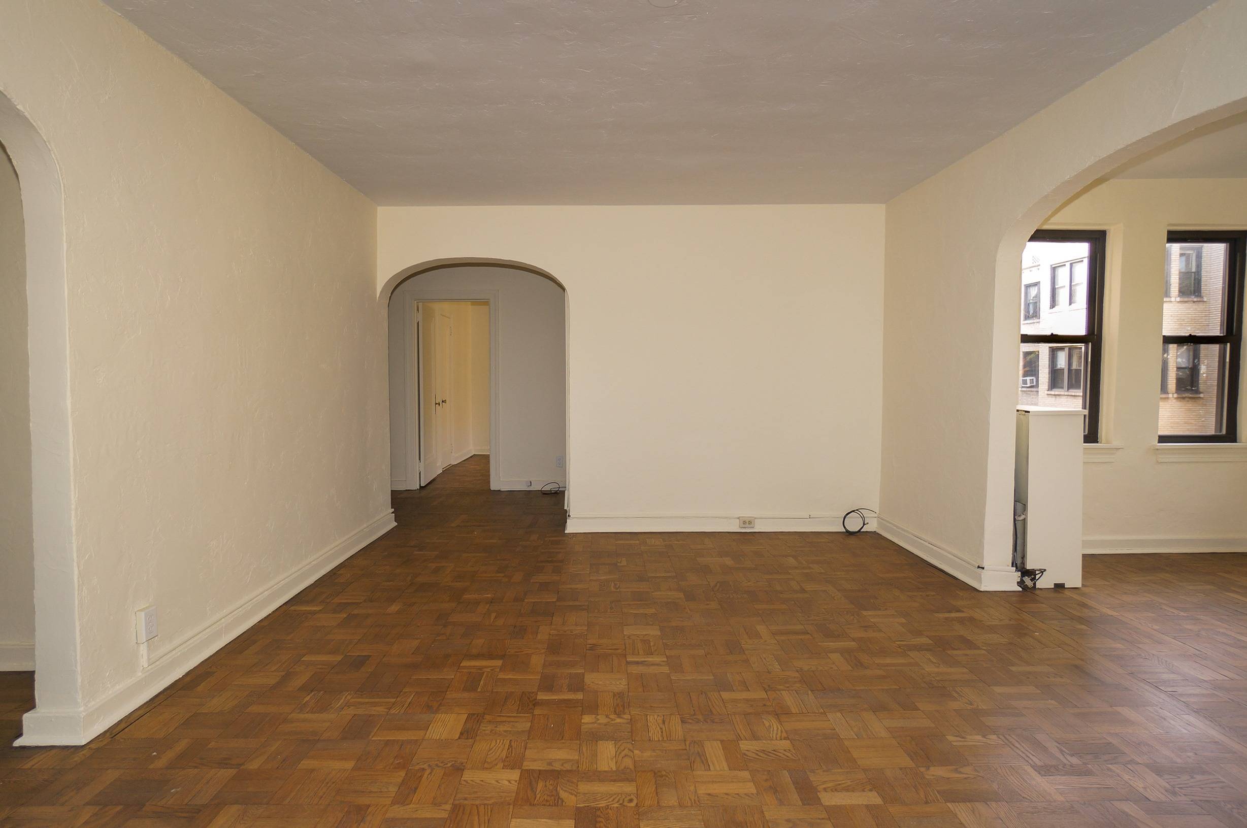 Living Room angle shows entry foyer, wood floors and white walls.