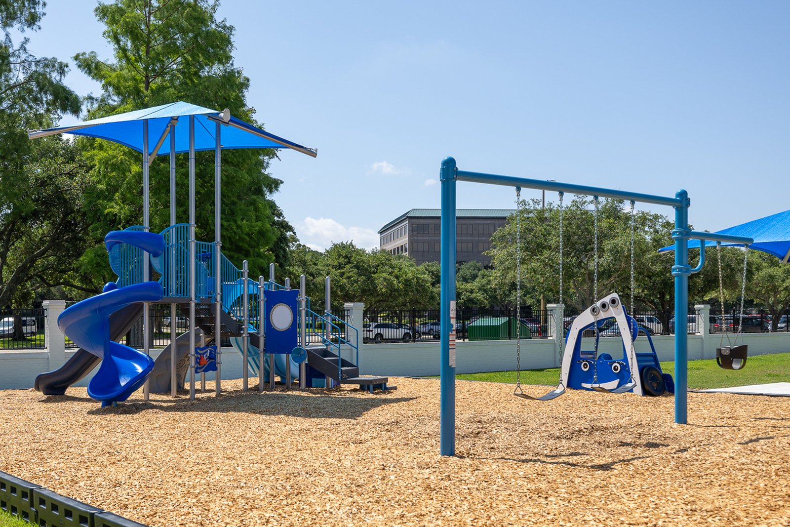 Colorful playground with swings, slides, and climbing structures under a sunny sky.