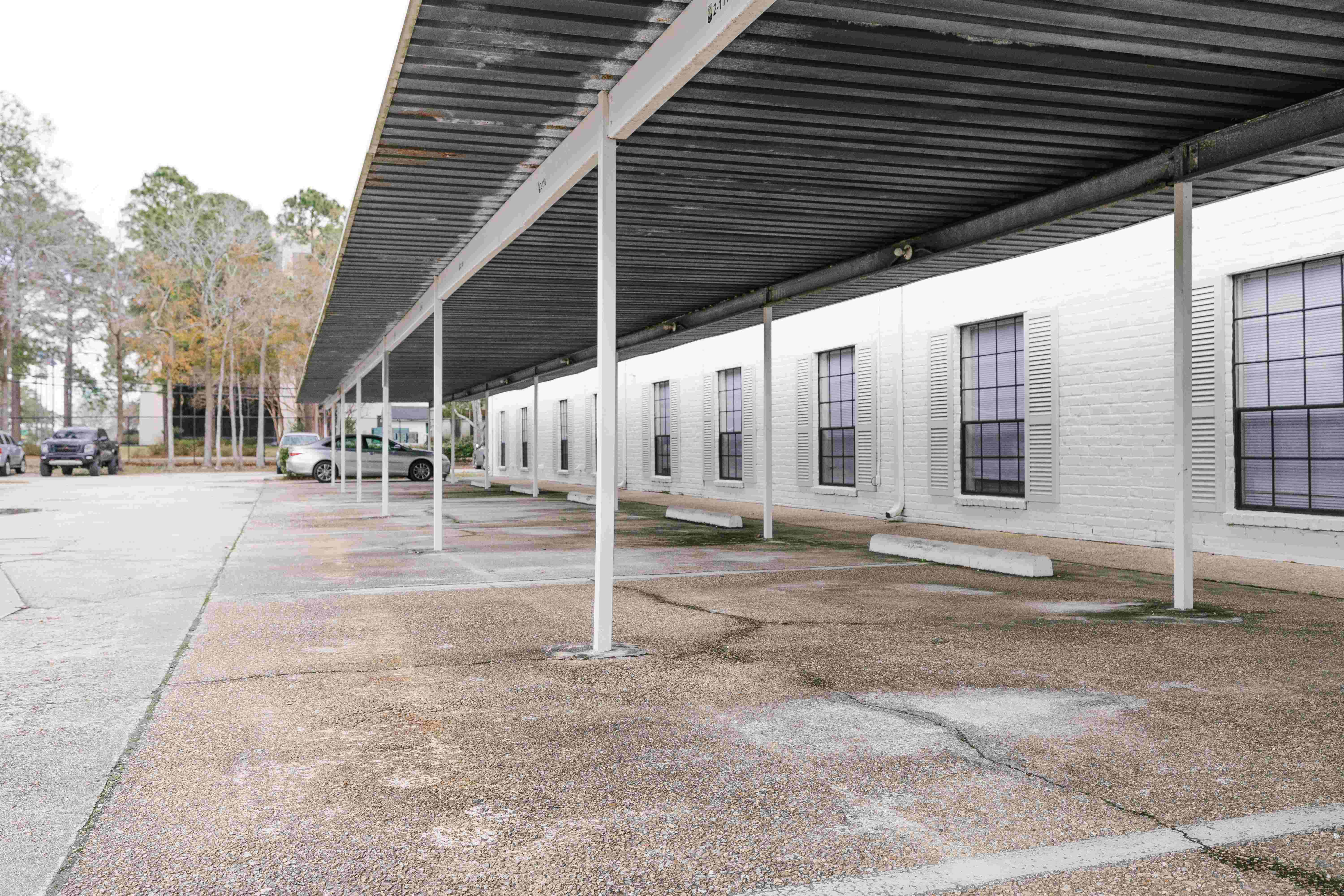 Spacious covered parking area outside a charming brick apartment complex, offering convenience and protection for residents\' vehicles.