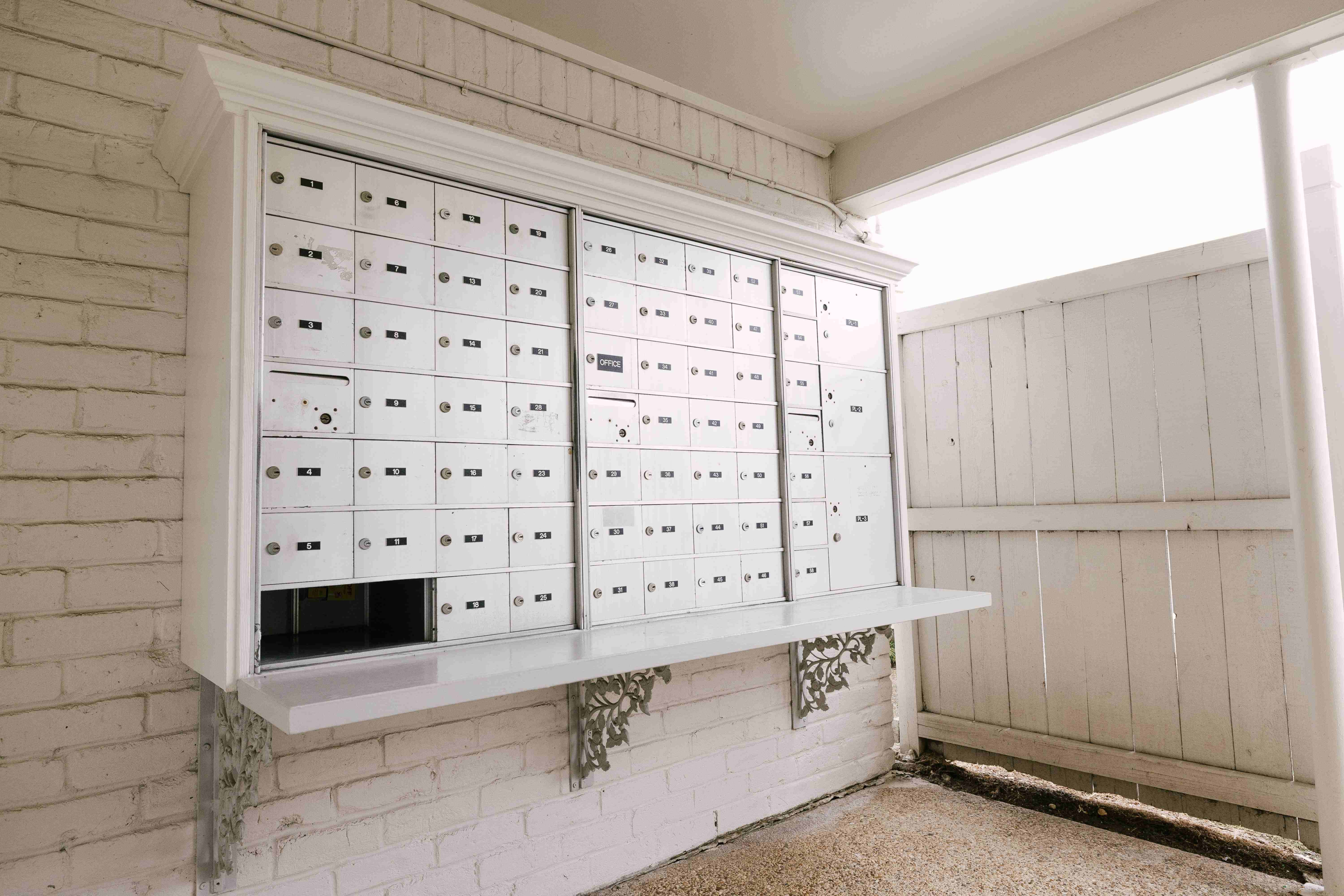 Charming and secure mailroom featuring a wall of individual white mailboxes with decorative detailing, perfect for apartment living.