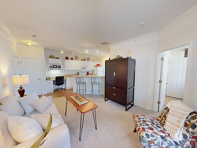 Charming open-concept living area with a cozy sofa, modern decor, and a bright kitchen, perfect for entertaining.