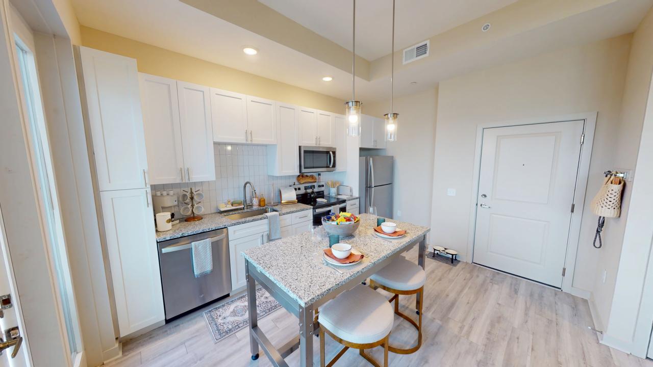 Chic modern kitchen with granite countertops, stainless steel appliances, and elegant pendant lighting, enhancing the open-concept layout.