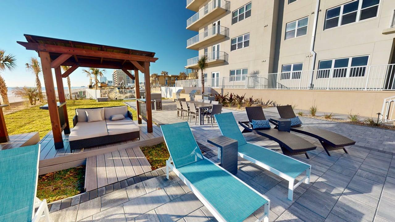 Luxurious outdoor lounge area with modern sun loungers, a cozy gazebo, and stunning ocean views, perfect for relaxation and entertaining.