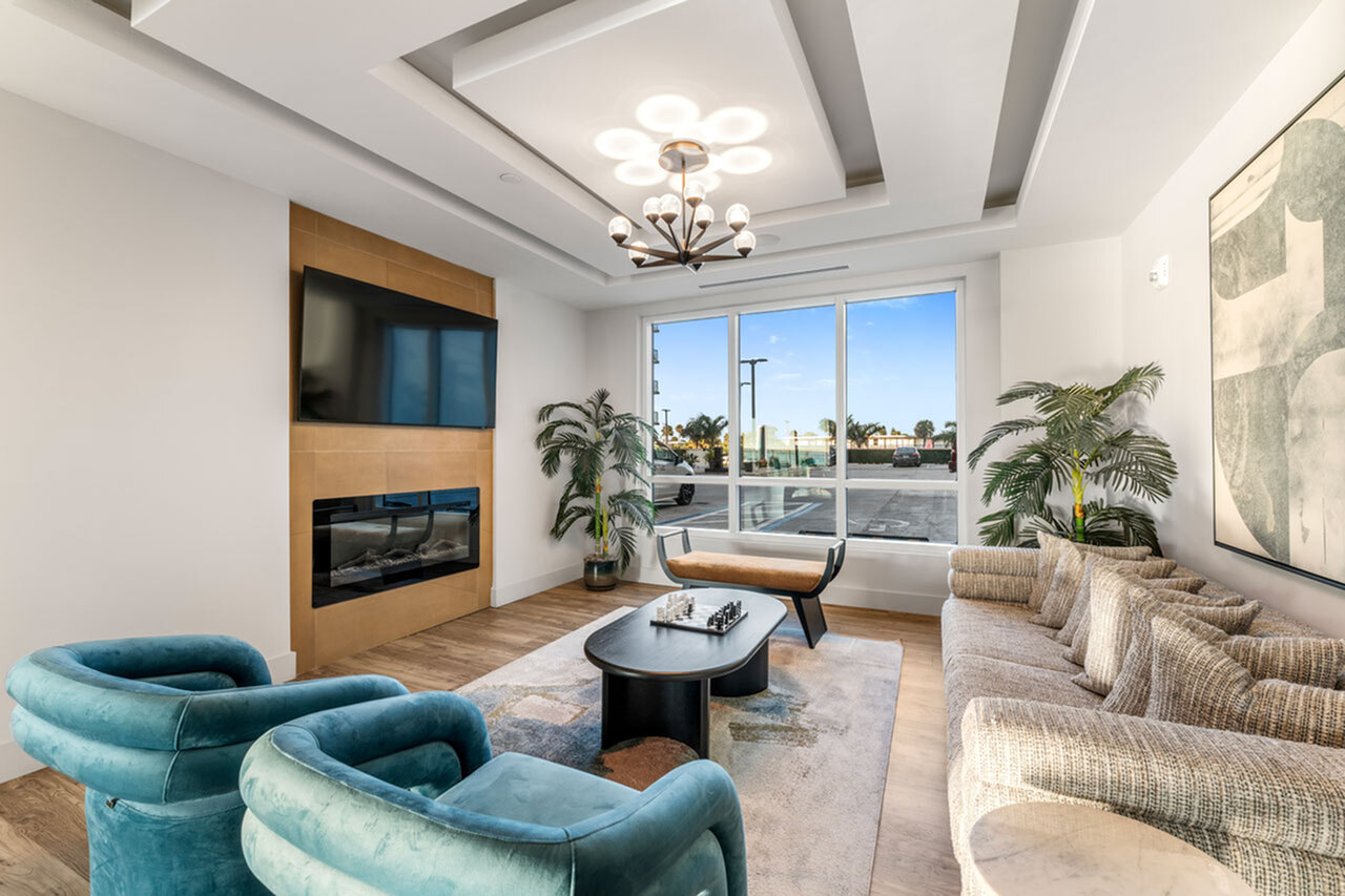 Elegant living room with modern decor, featuring plush armchairs, a contemporary sofa, a sleek fireplace, and large windows.