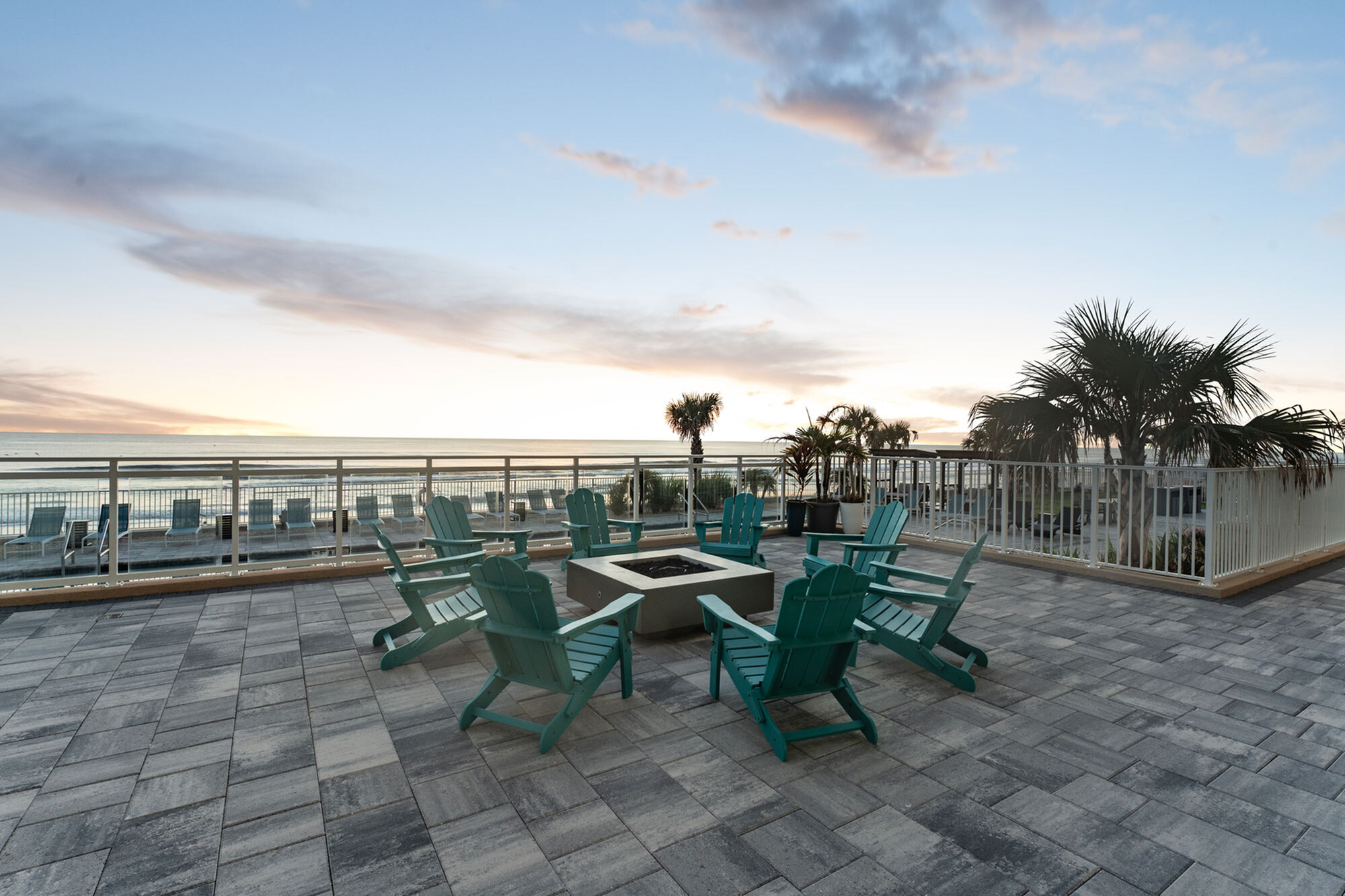 Luxurious oceanfront terrace with stylish lounge chairs, fire pit, and breathtaking sunset views.
