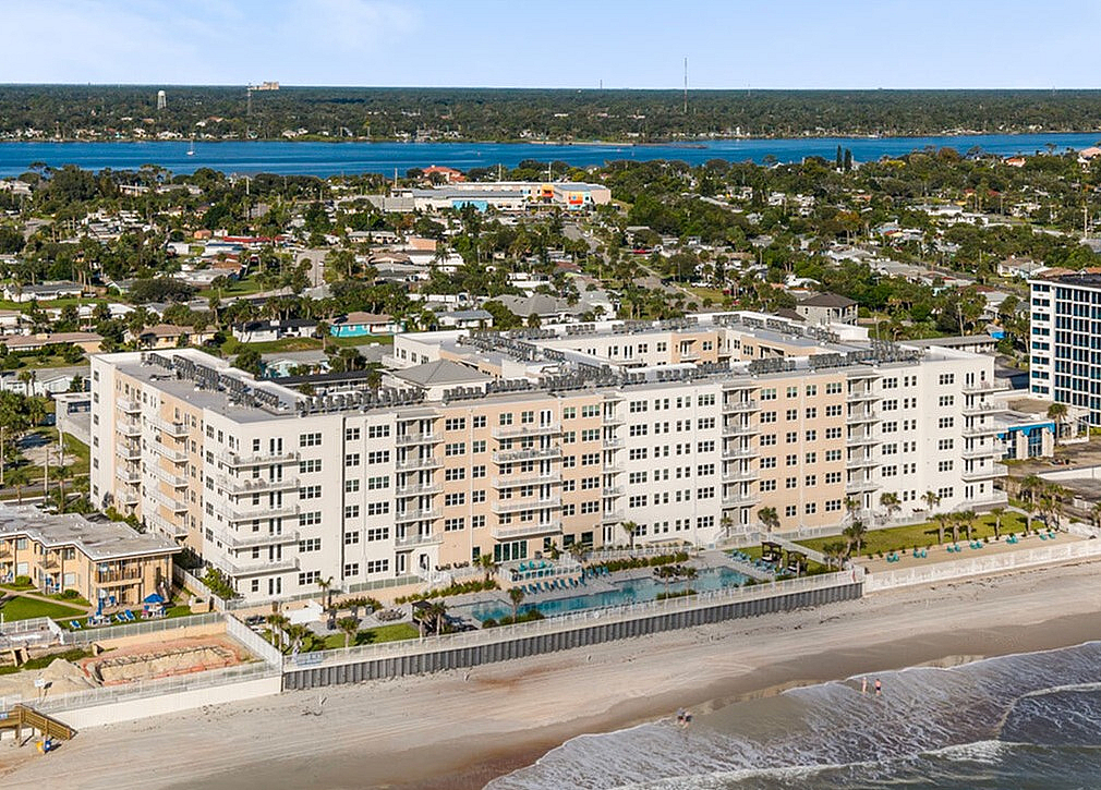 Breathtaking aerial view of luxurious beachfront apartment complex with panoramic ocean views and serene coastal surroundings.