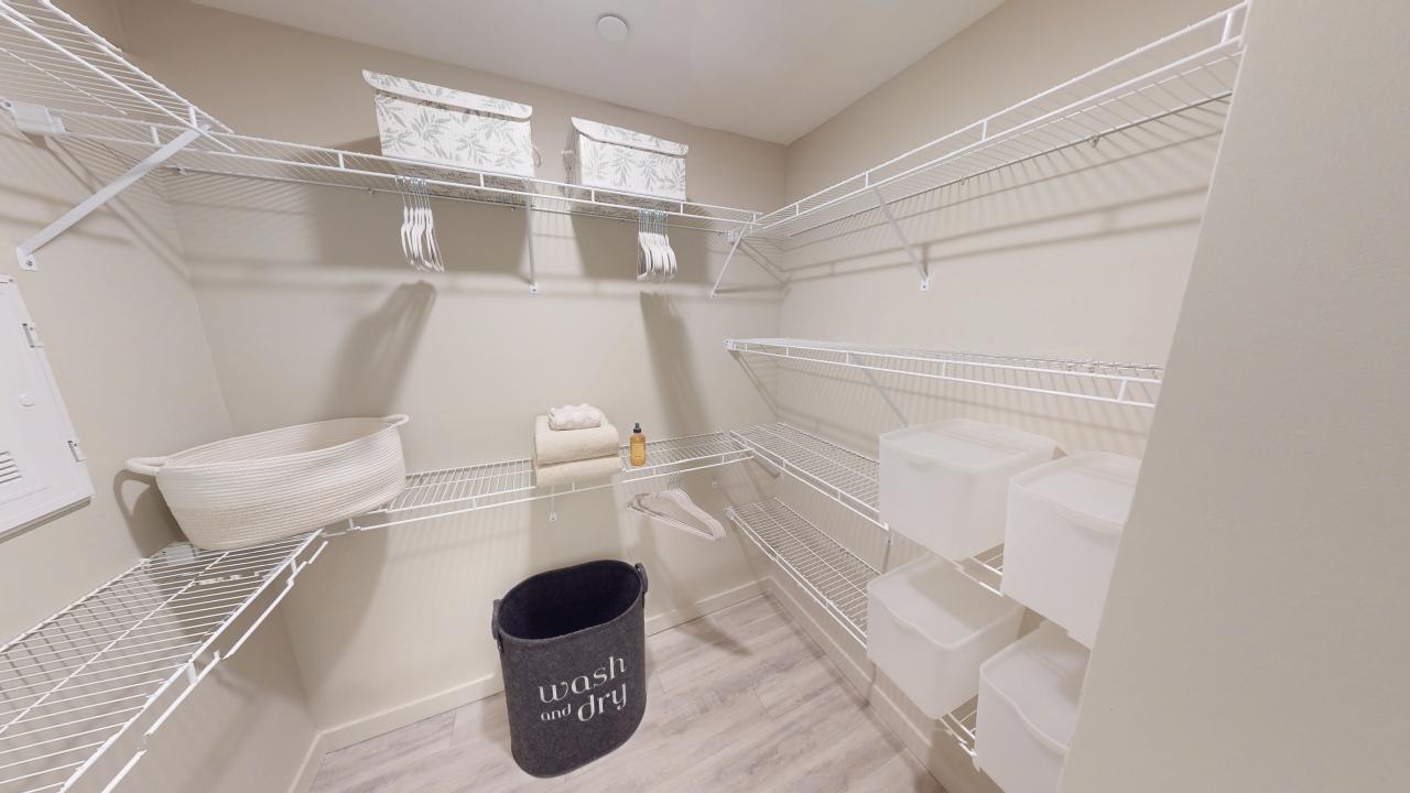 Spacious walk-in closet with organized shelving, storage bins, and a chic laundry basket, perfect for modern living.