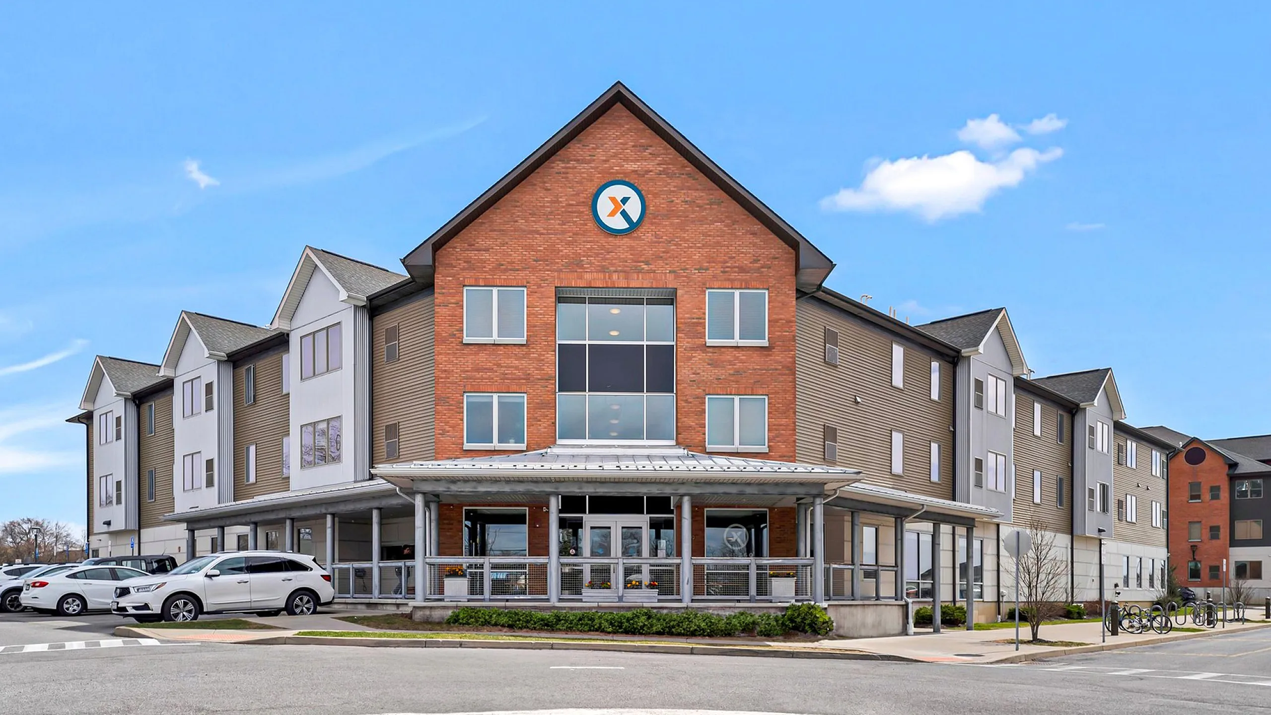 Modern residential building with stylish brick facade and ample parking, showcasing contemporary architectural design.