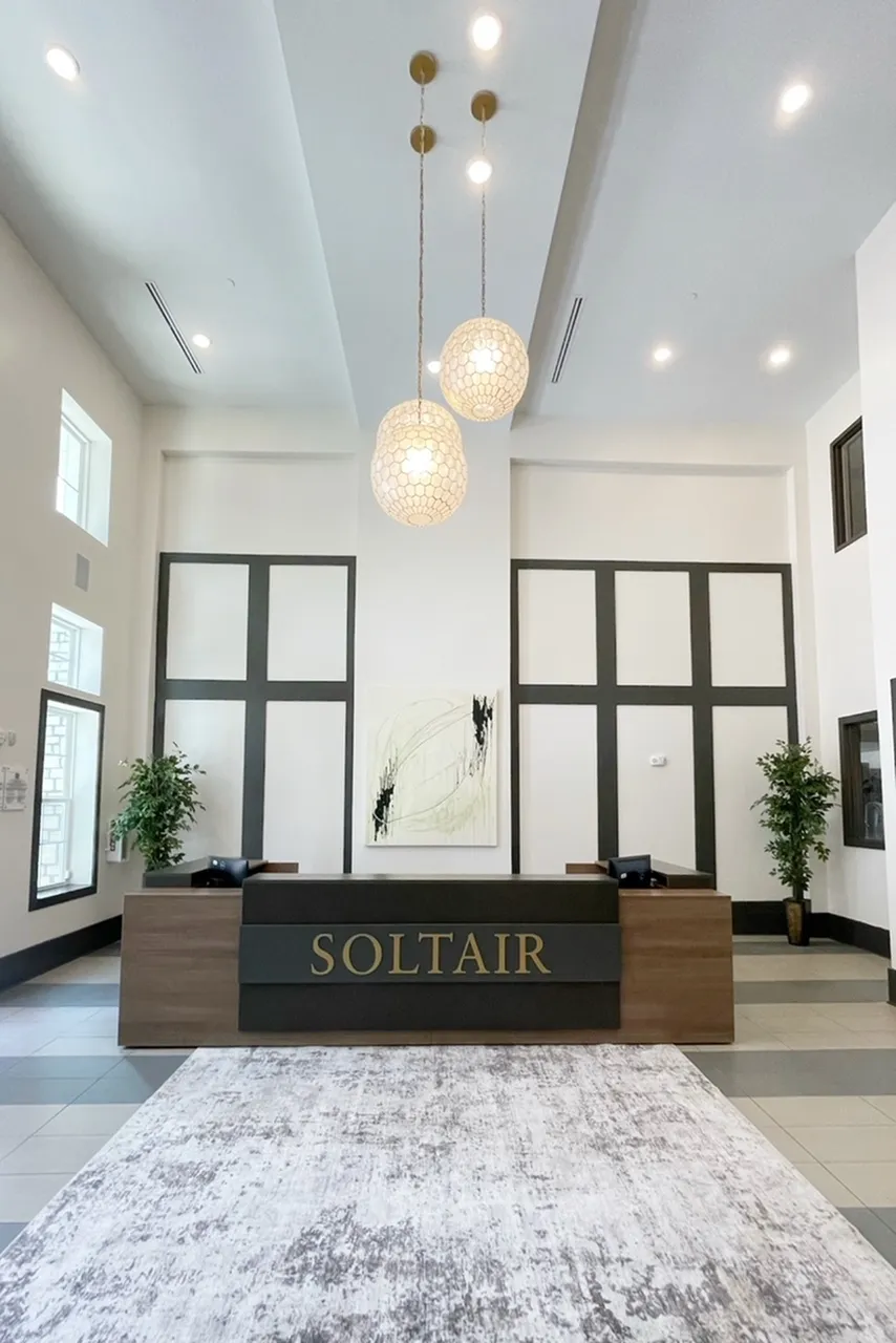 Elegant apartment lobby at Soltair with modern decor, stylish pendant lighting, and inviting reception area.