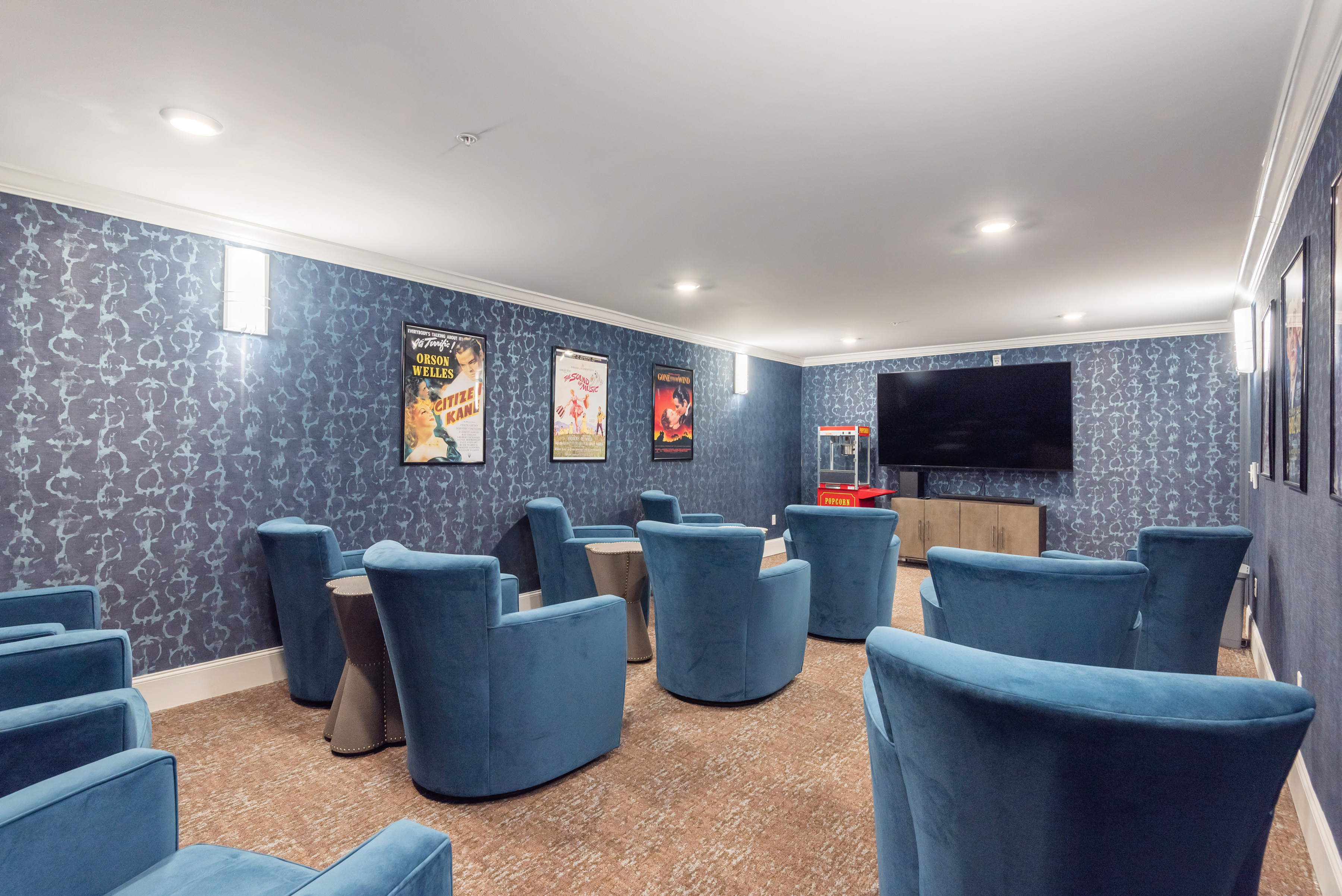Chic home theater room with plush blue seating, modern decor, and a large screen for an immersive viewing experience.