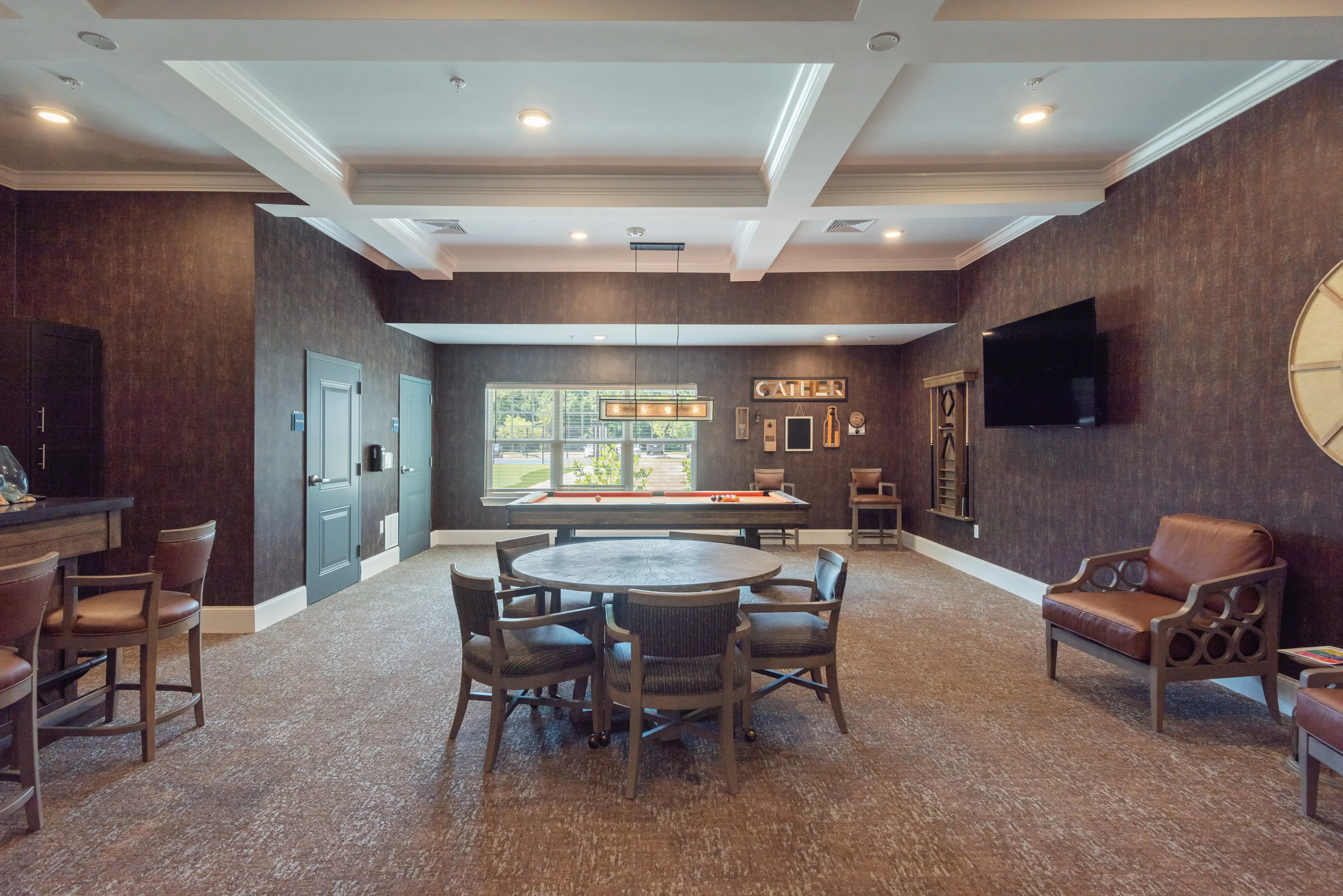 Inviting recreational room featuring a modern pool table, comfortable seating, and elegant decor with a warm ambiance.