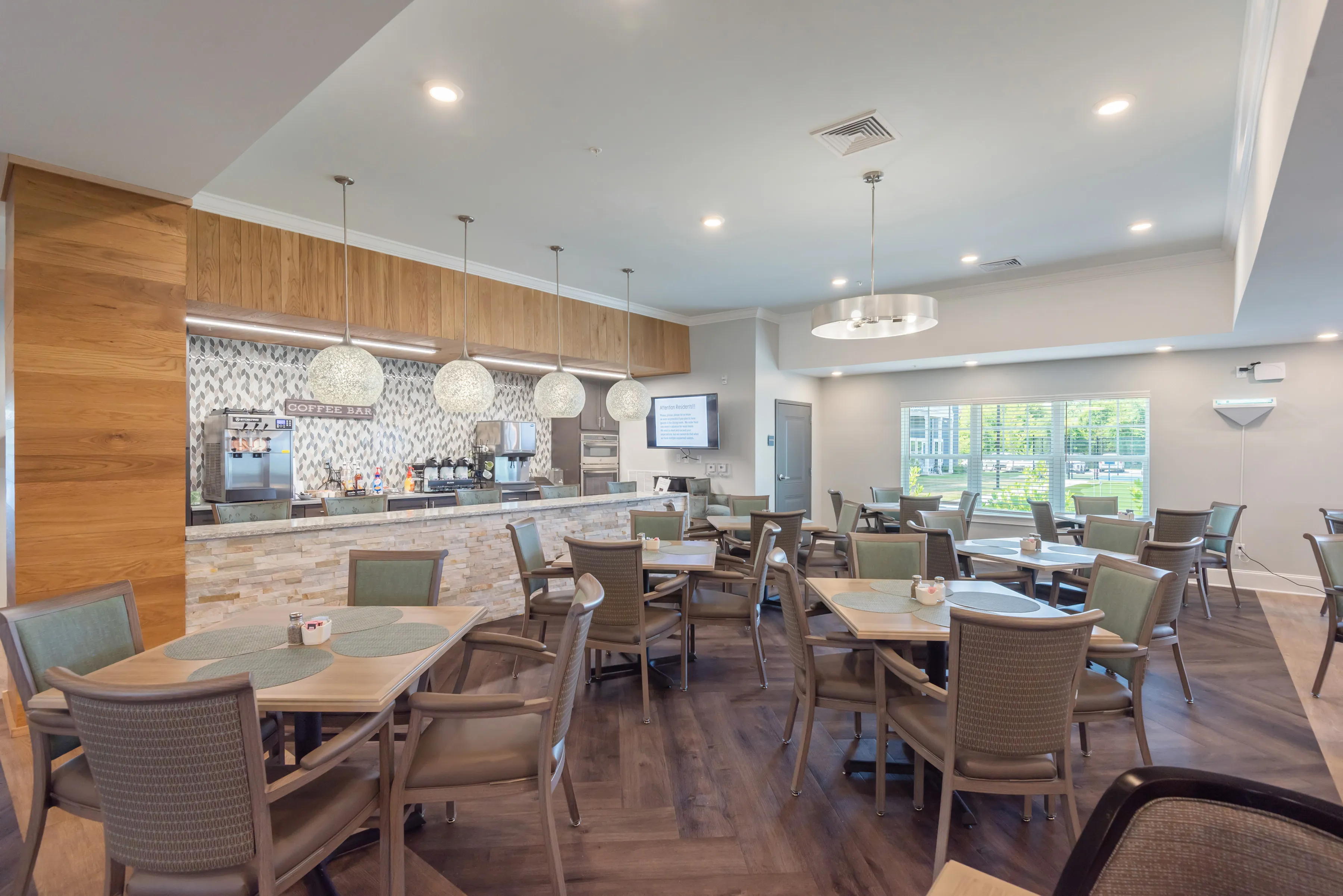 Elegant community dining area with modern decor, featuring a stylish coffee bar and abundant natural light.