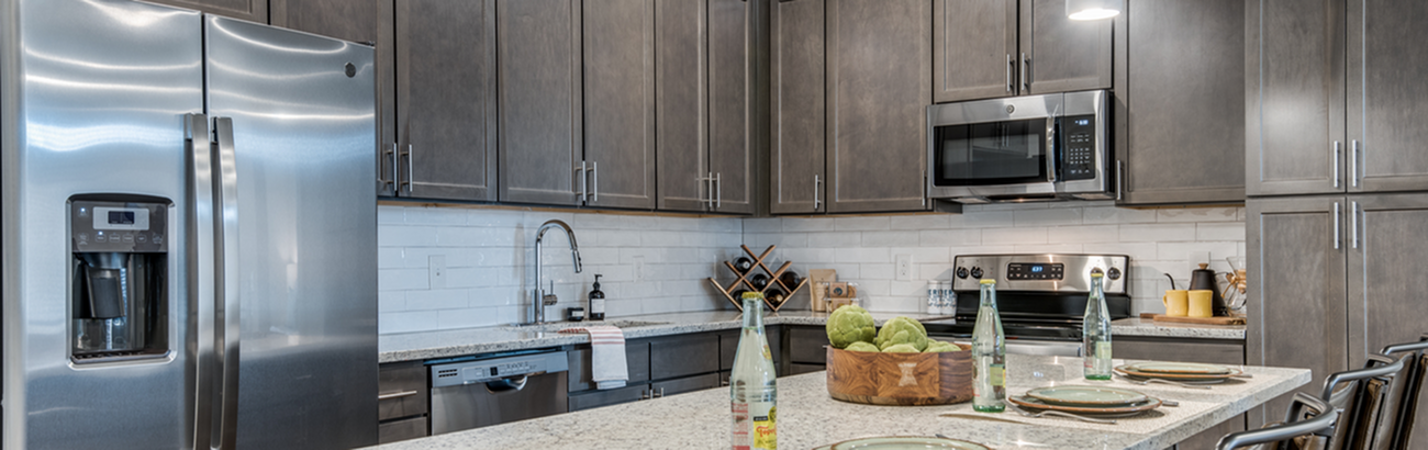 Modern kitchen with sleek stainless steel appliances, elegant gray cabinets, and a spacious granite island perfect for entertaining.