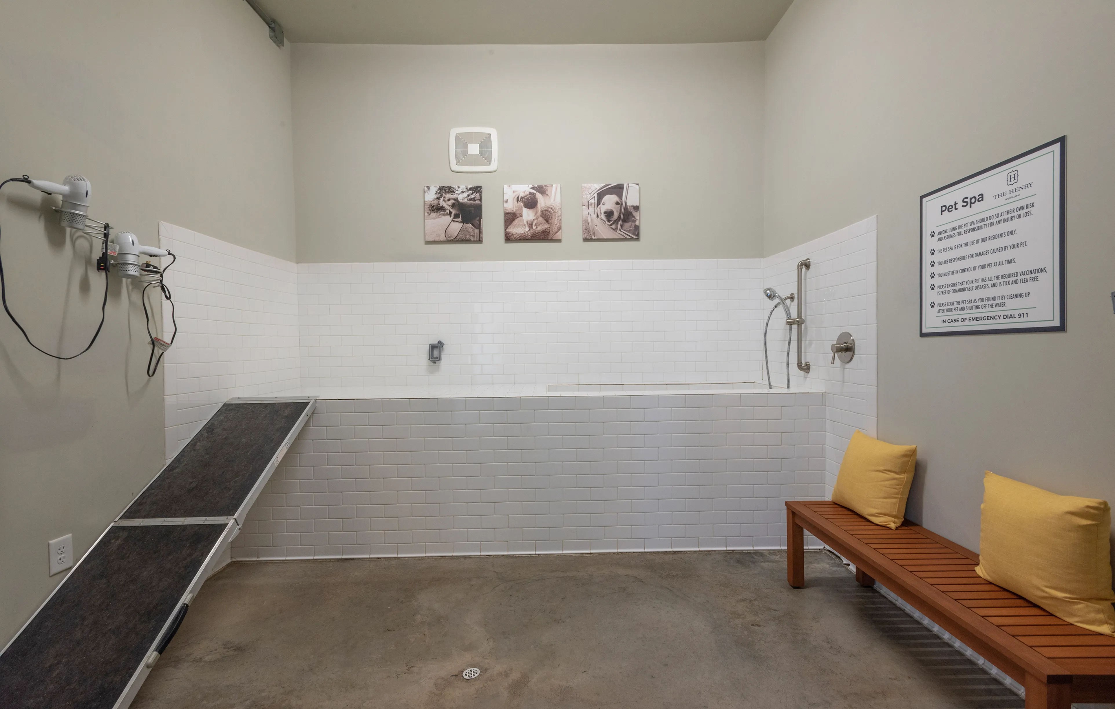 Modern pet spa area with sleek washing station, tiled walls, and cozy wooden bench with cushions.