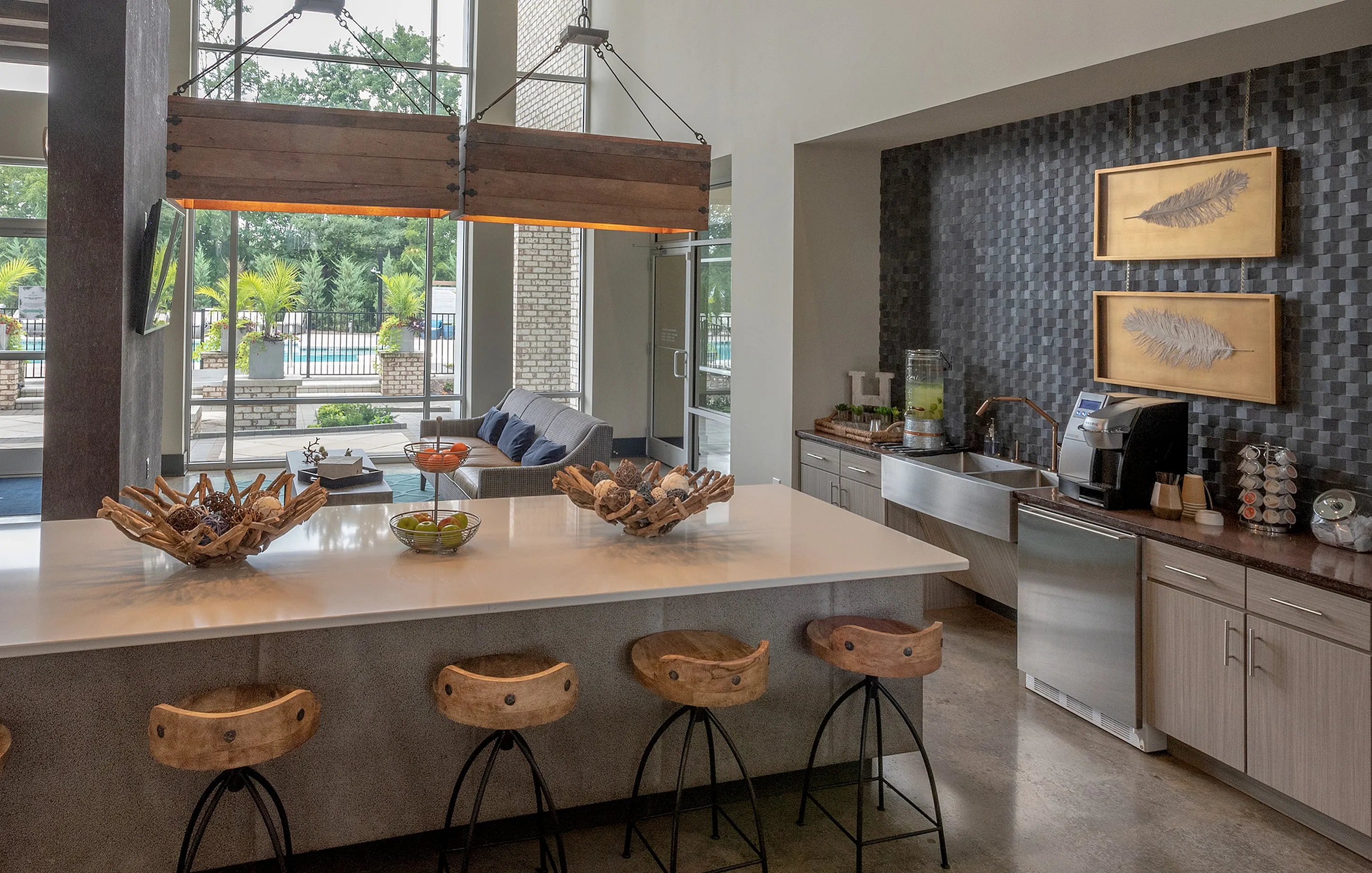 Luxurious contemporary kitchen with chic island seating, modern appliances, and expansive poolside views through floor-to-ceiling windows, perfect for entertaining.