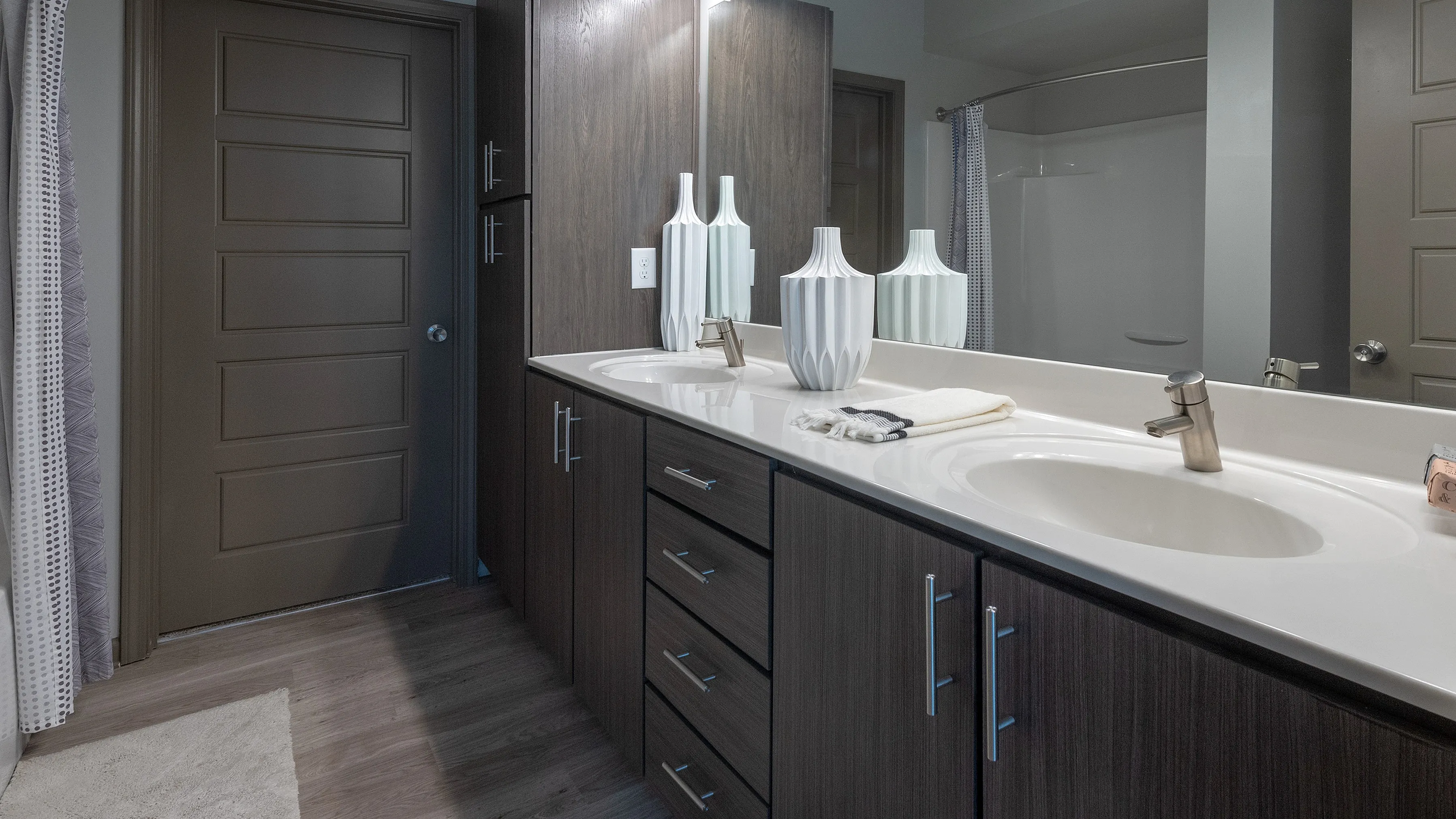 Modern bathroom with elegant double sink vanity, sleek dark wood cabinets, and ambient lighting.