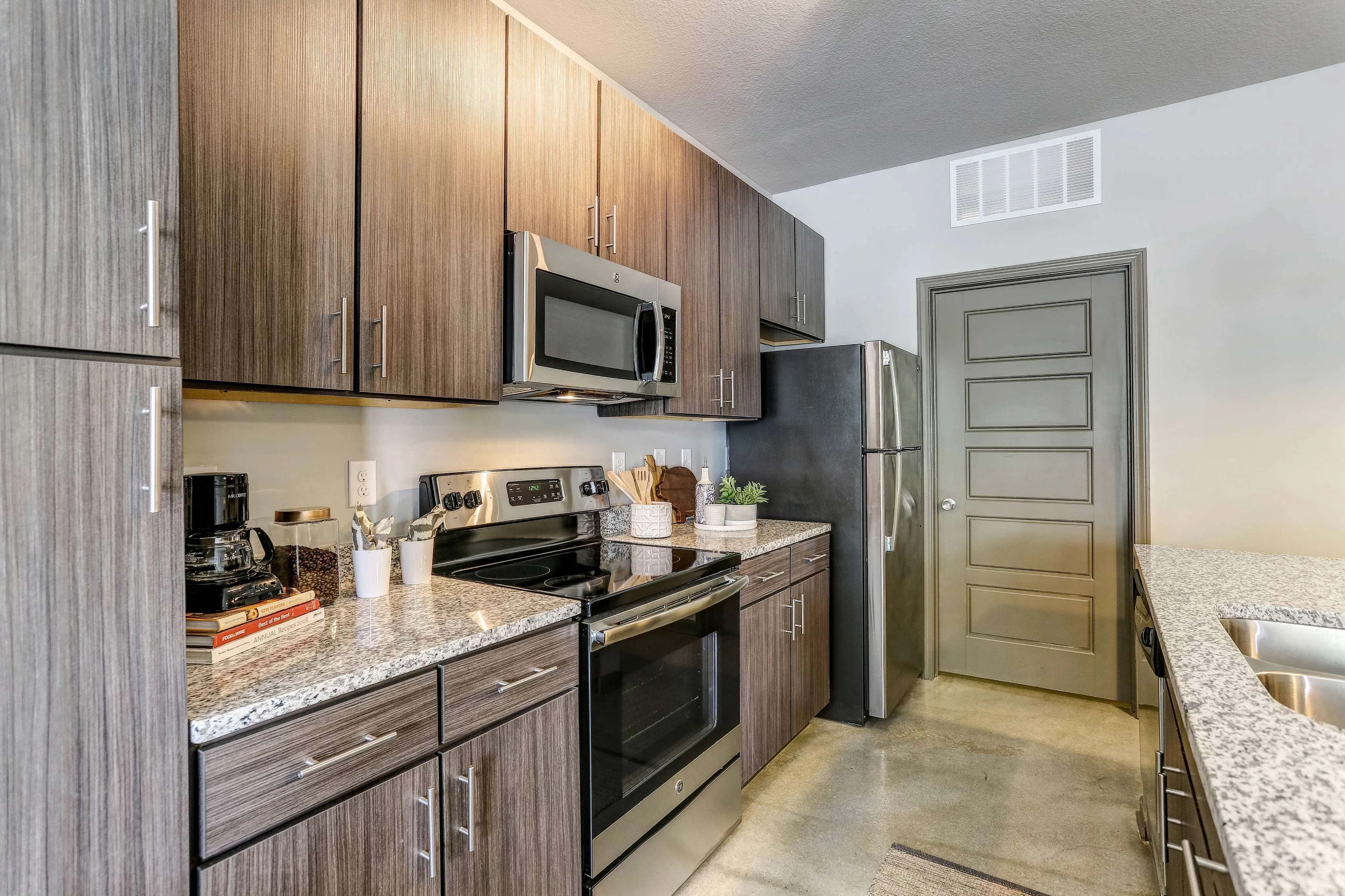 Modern kitchen with sleek dark wood cabinets, granite countertops, stainless steel appliances, and stylish finishes.