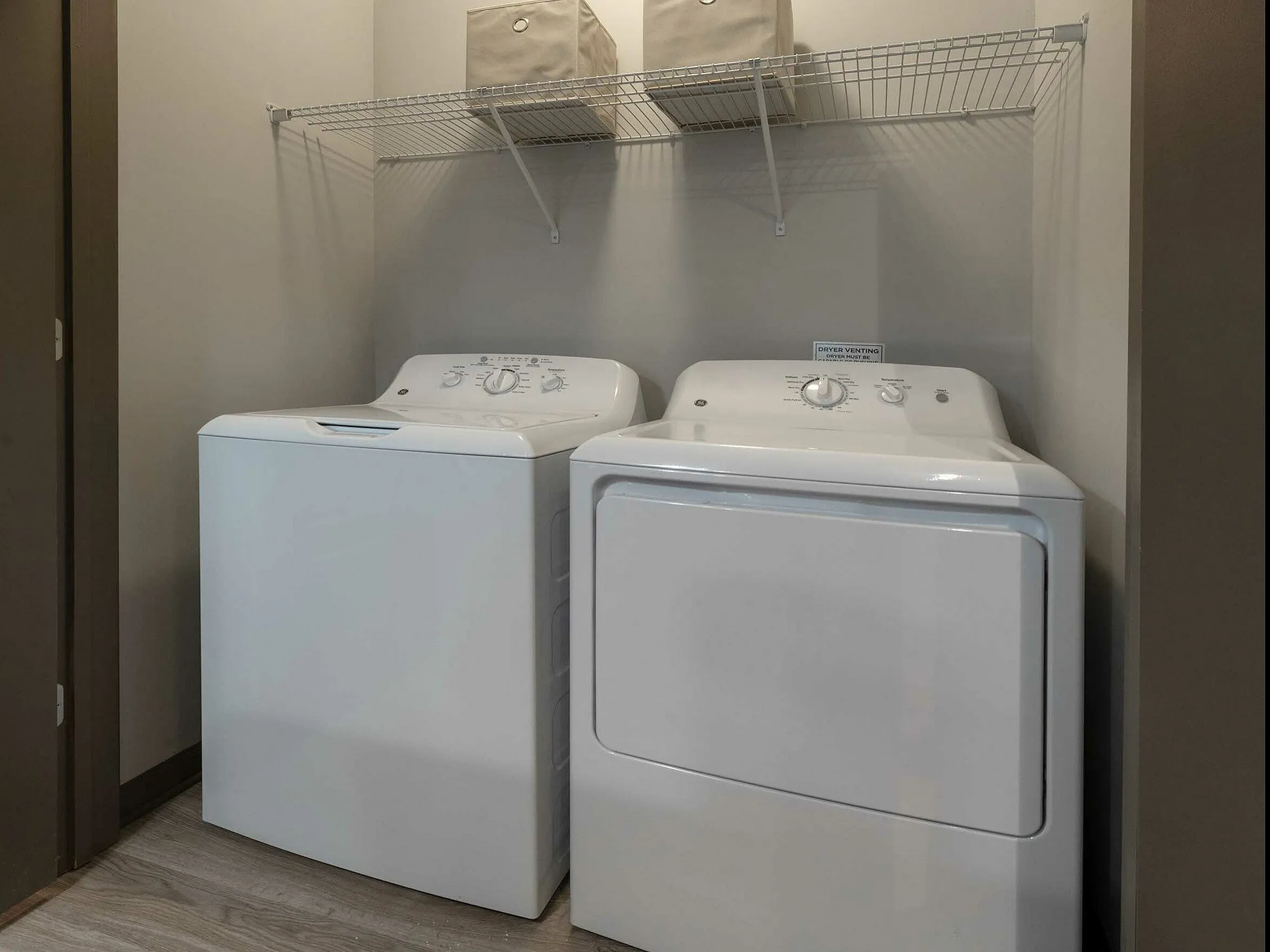 Elegant laundry nook with modern washer and dryer, featuring convenient shelving and stylish design.