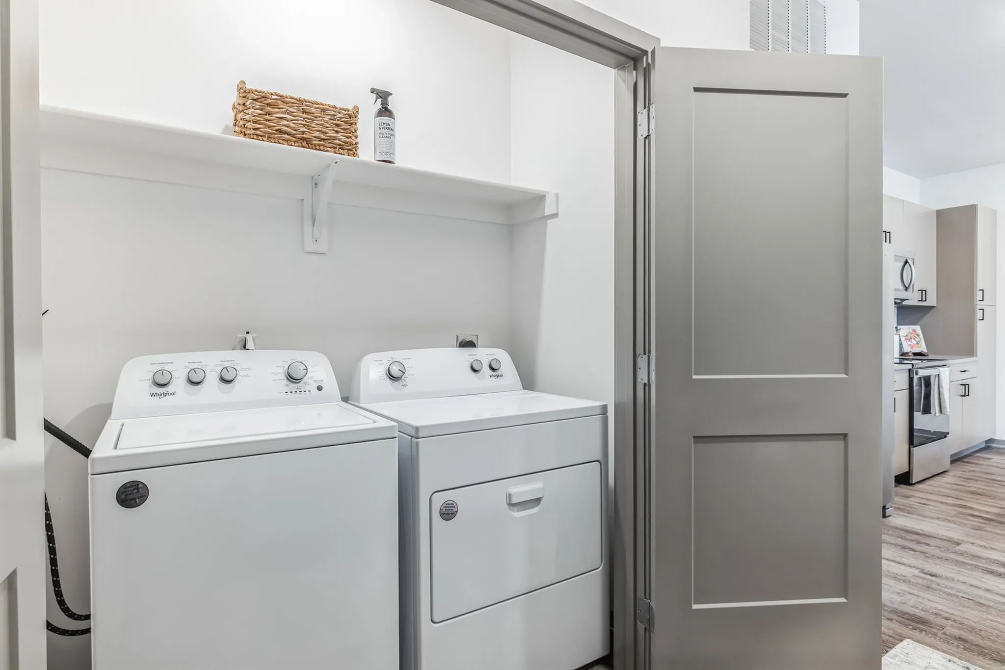 Modern laundry area with front-loading washer and dryer, featuring elegant shelving for storage and sleek folding doors.