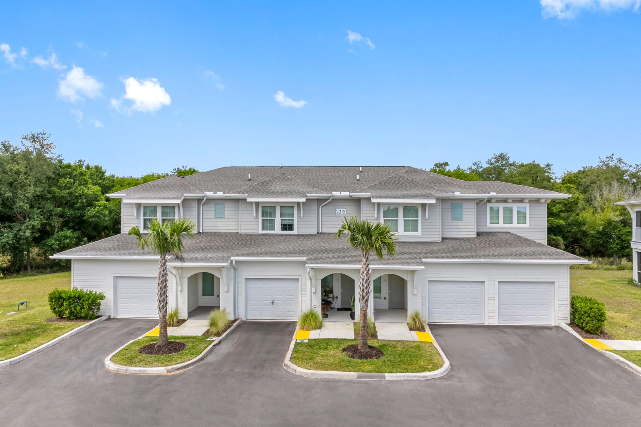Charming townhomes with stylish architecture, twin garages, and inviting palm trees set against a serene backdrop.