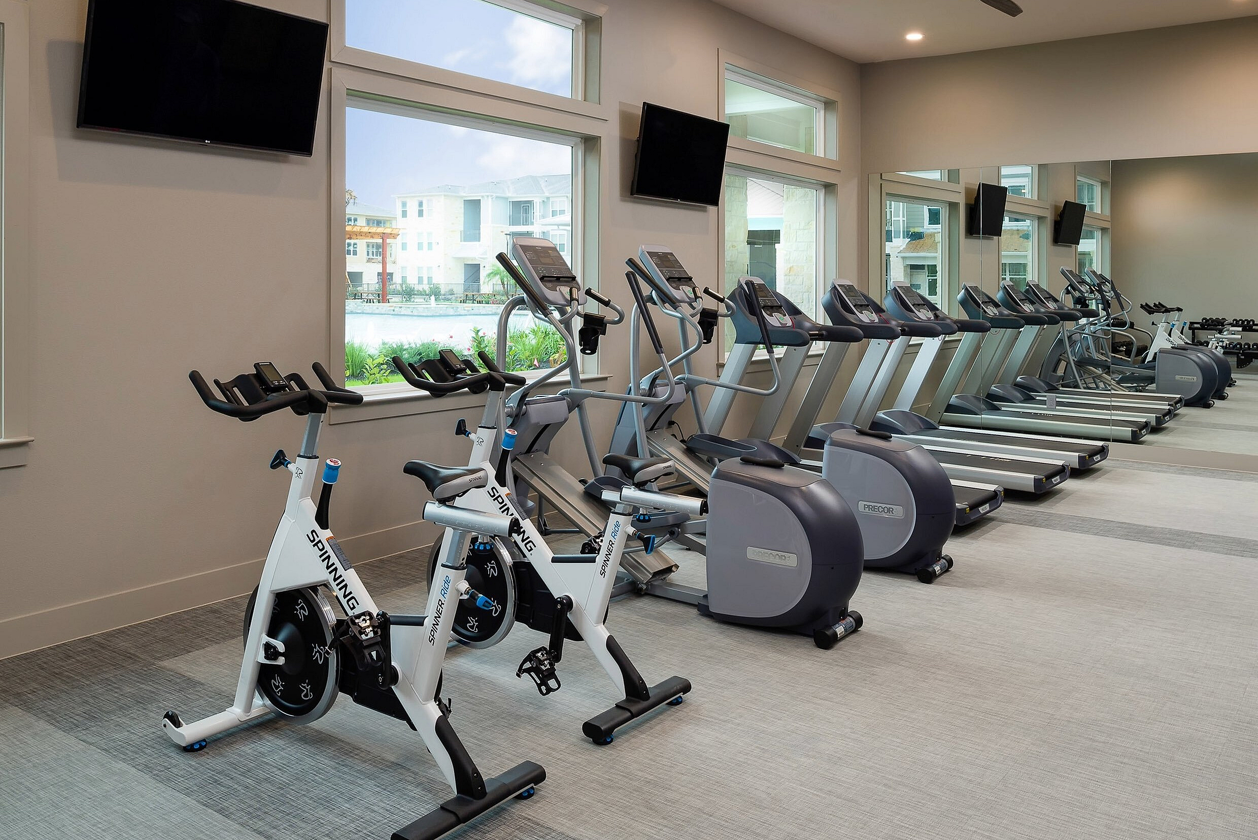 Modern fitness center with bright natural lighting, featuring sleek exercise bikes and state-of-the-art treadmills.