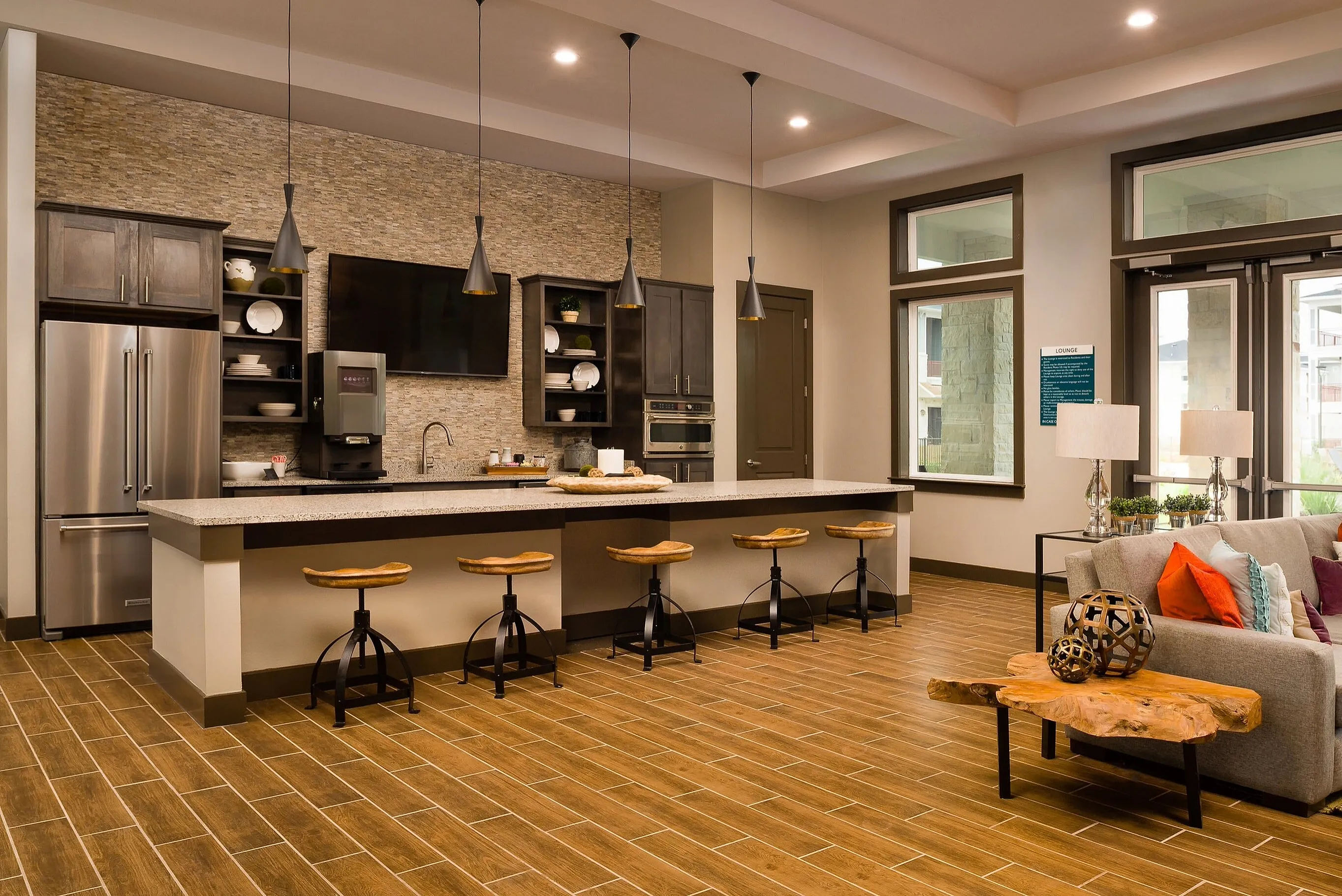 Modern kitchen and living area with sleek countertops, bar seating, and stylish decor in a bright, open space.