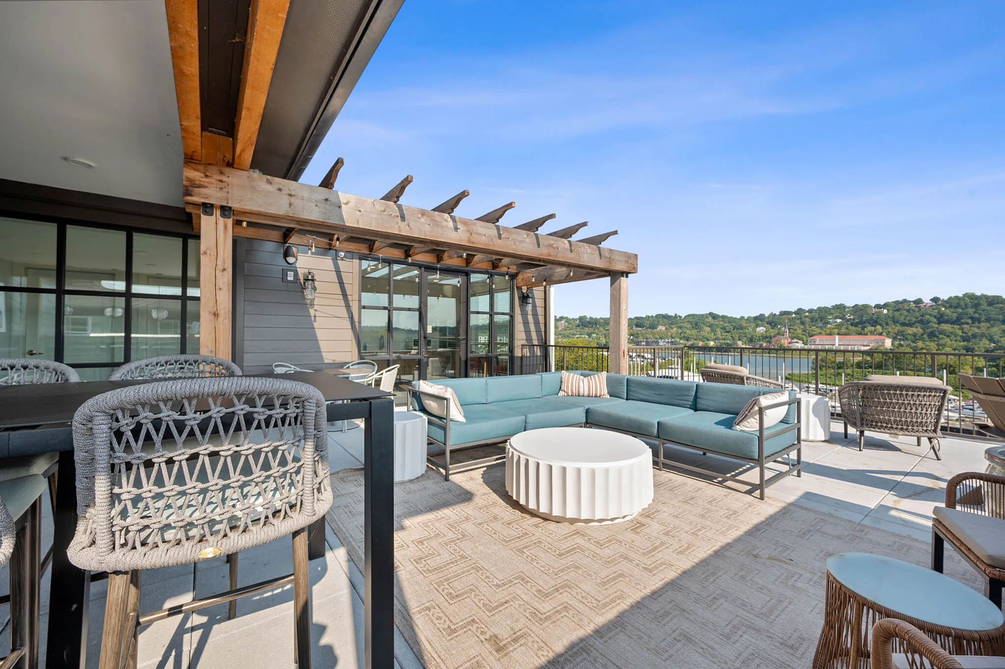 Luxurious outdoor terrace featuring a modern pergola, stylish seating areas, and breathtaking views of lush greenery and blue skies.